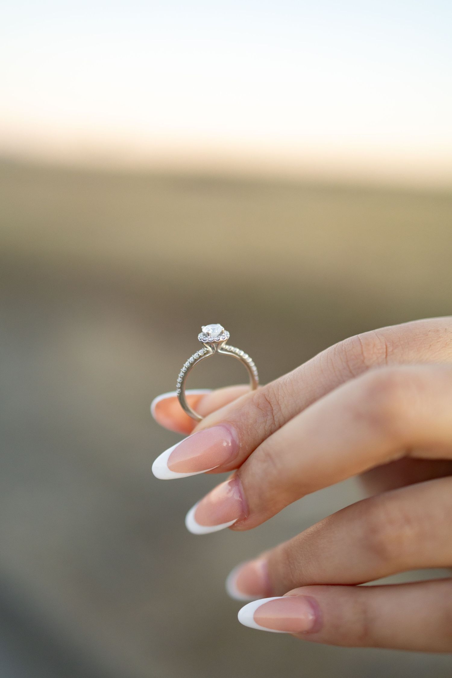 Close-up sequence of hands displaying a diamond engagement ring with French manicured nails.