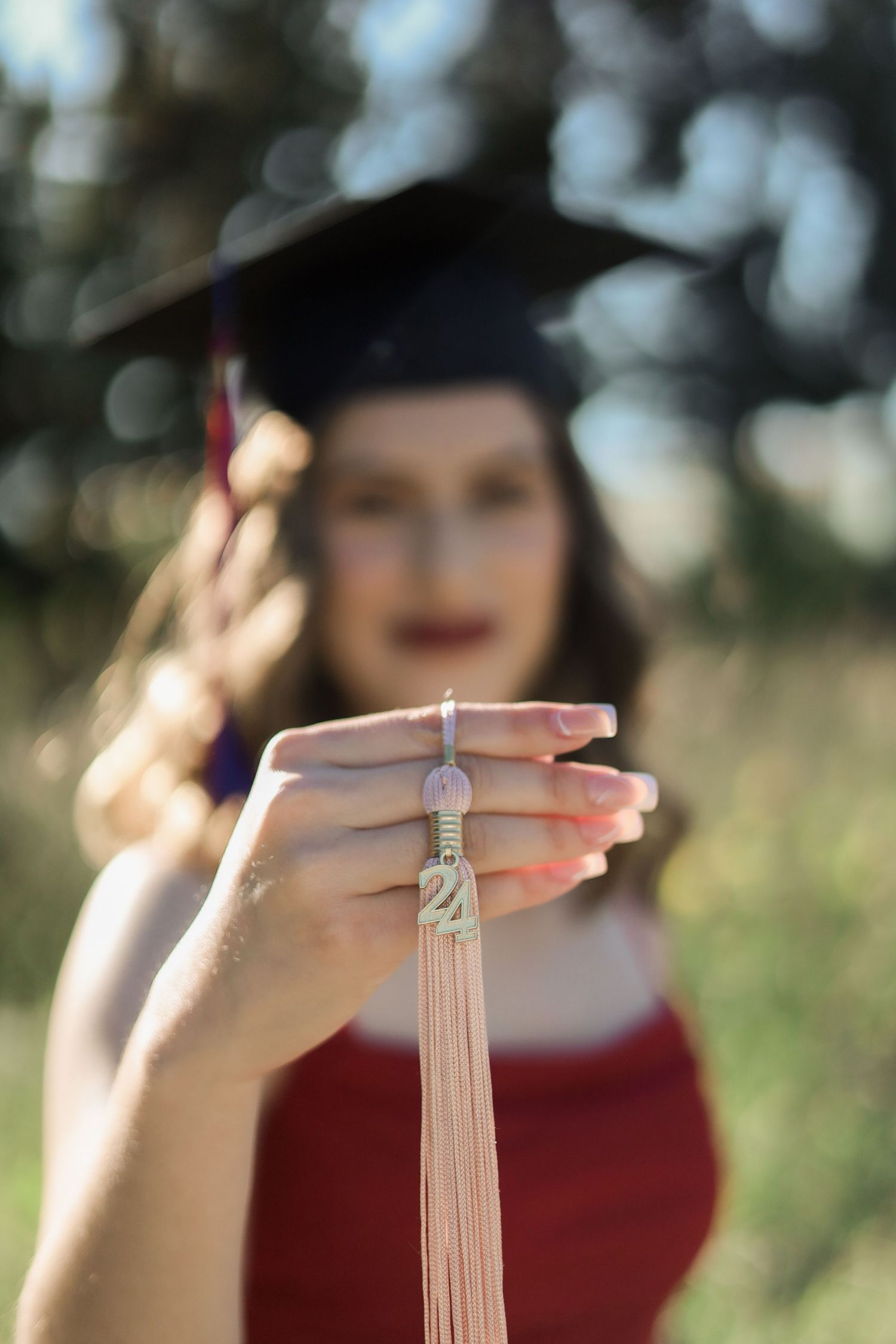 Close-up shots of hands holding graduation tassels against a blurred outdoor background.