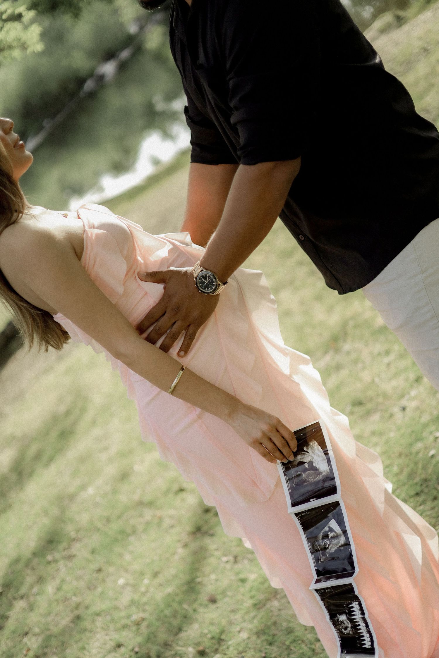Series of hands adjusting a flowing pink dress against a soft green grass background.