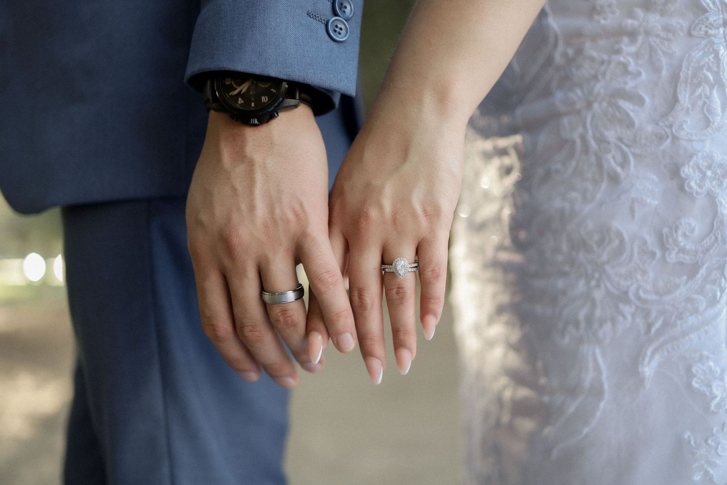 Close-up of wedding rings and lace details on formal attire.