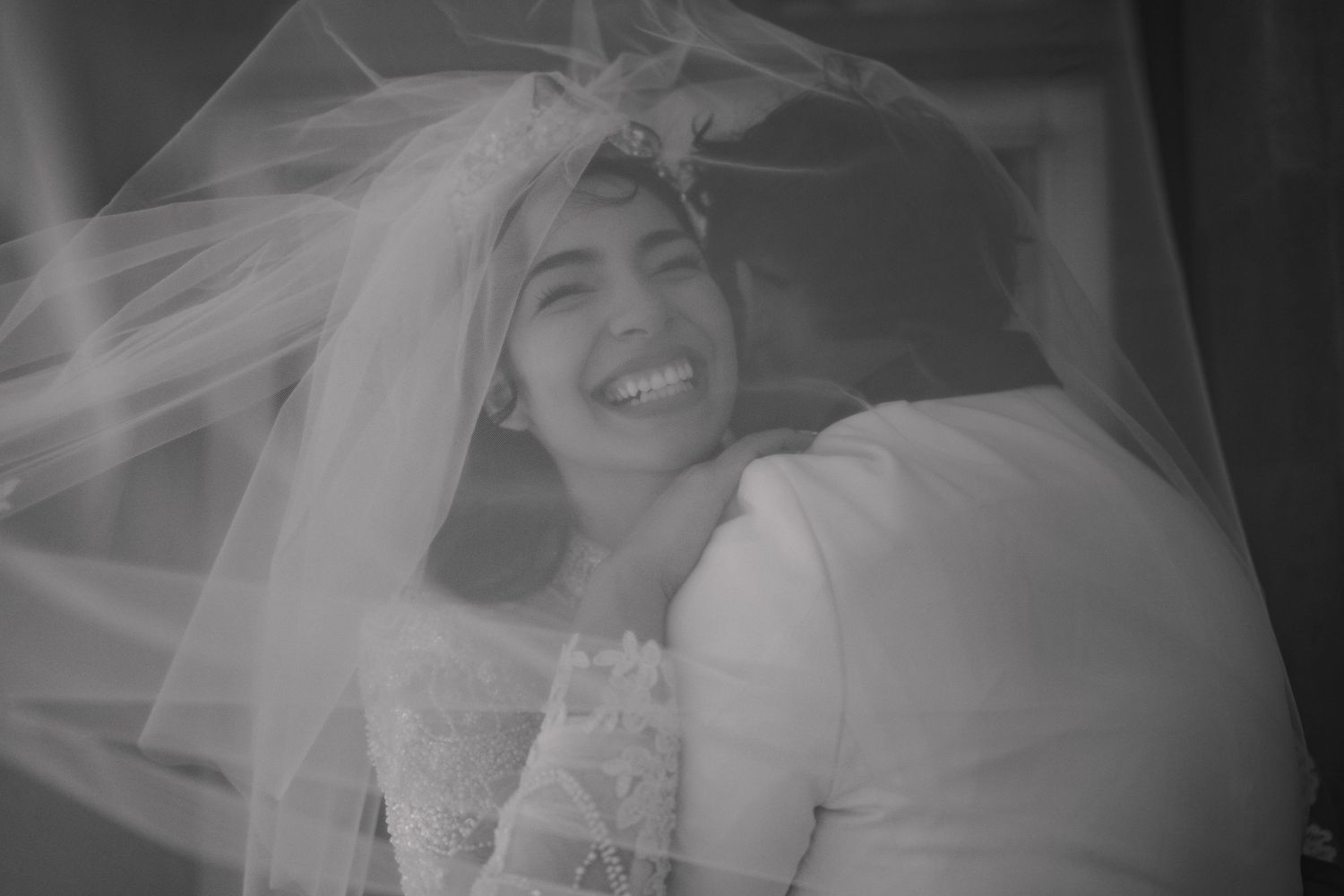 Elegant black and white portrait series capturing bridal moments through flowing veil.