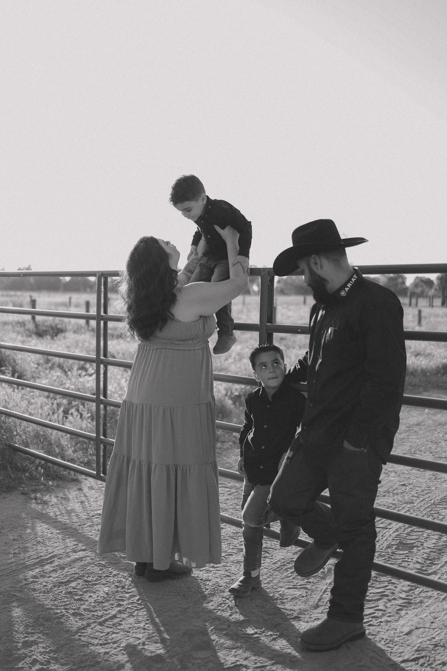 Family group gathered near wooden fence during golden hour photography session.