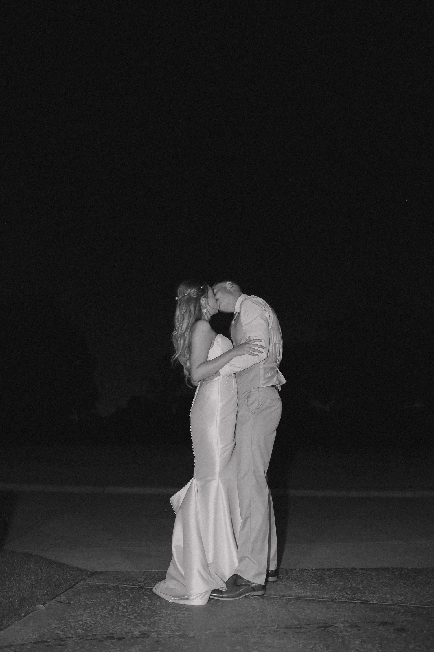 A black and white photo captures a couple's romantic embrace during their wedding night.