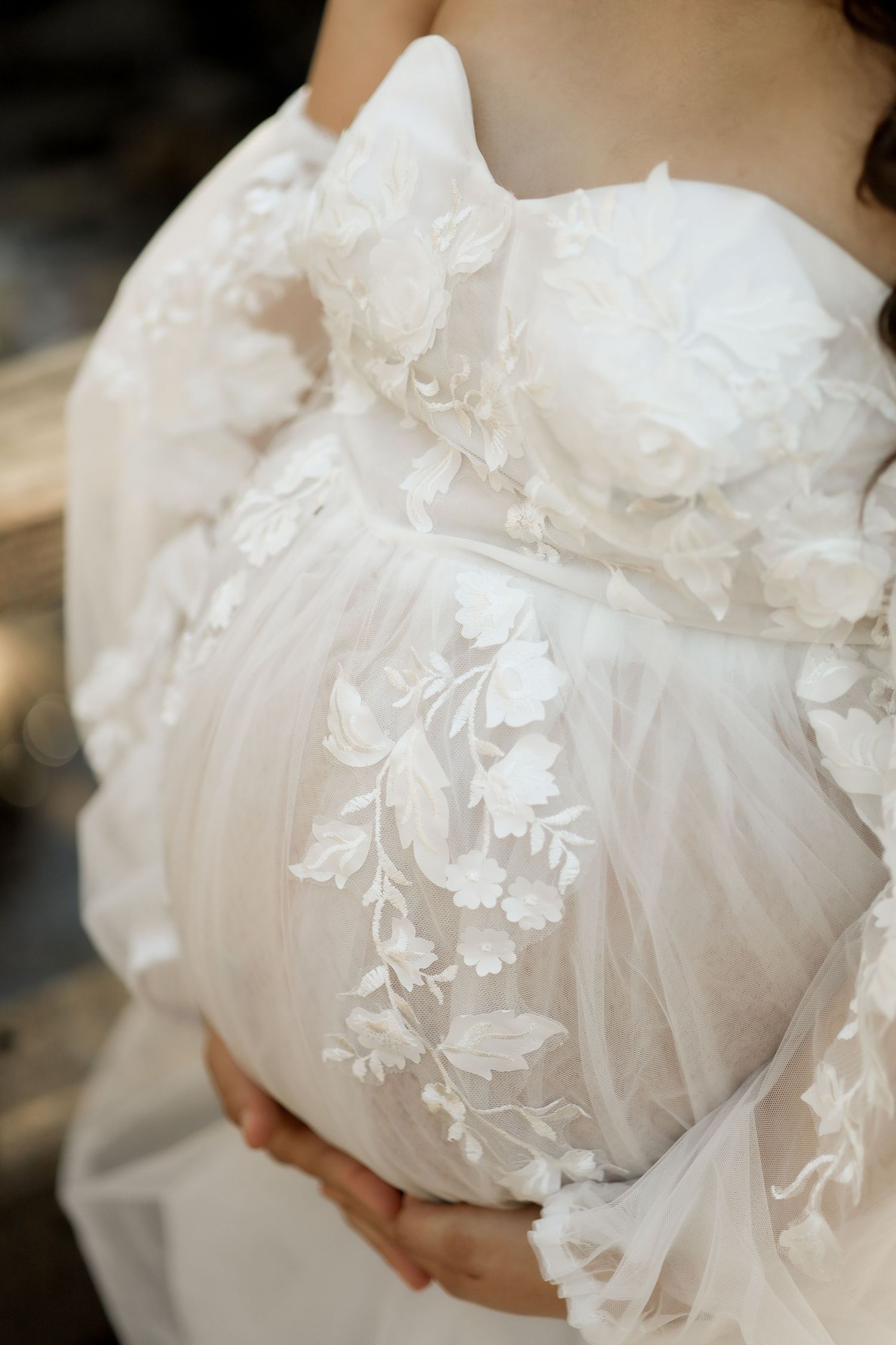 Close-up details of delicate white lace and floral embroidery on a wedding dress.