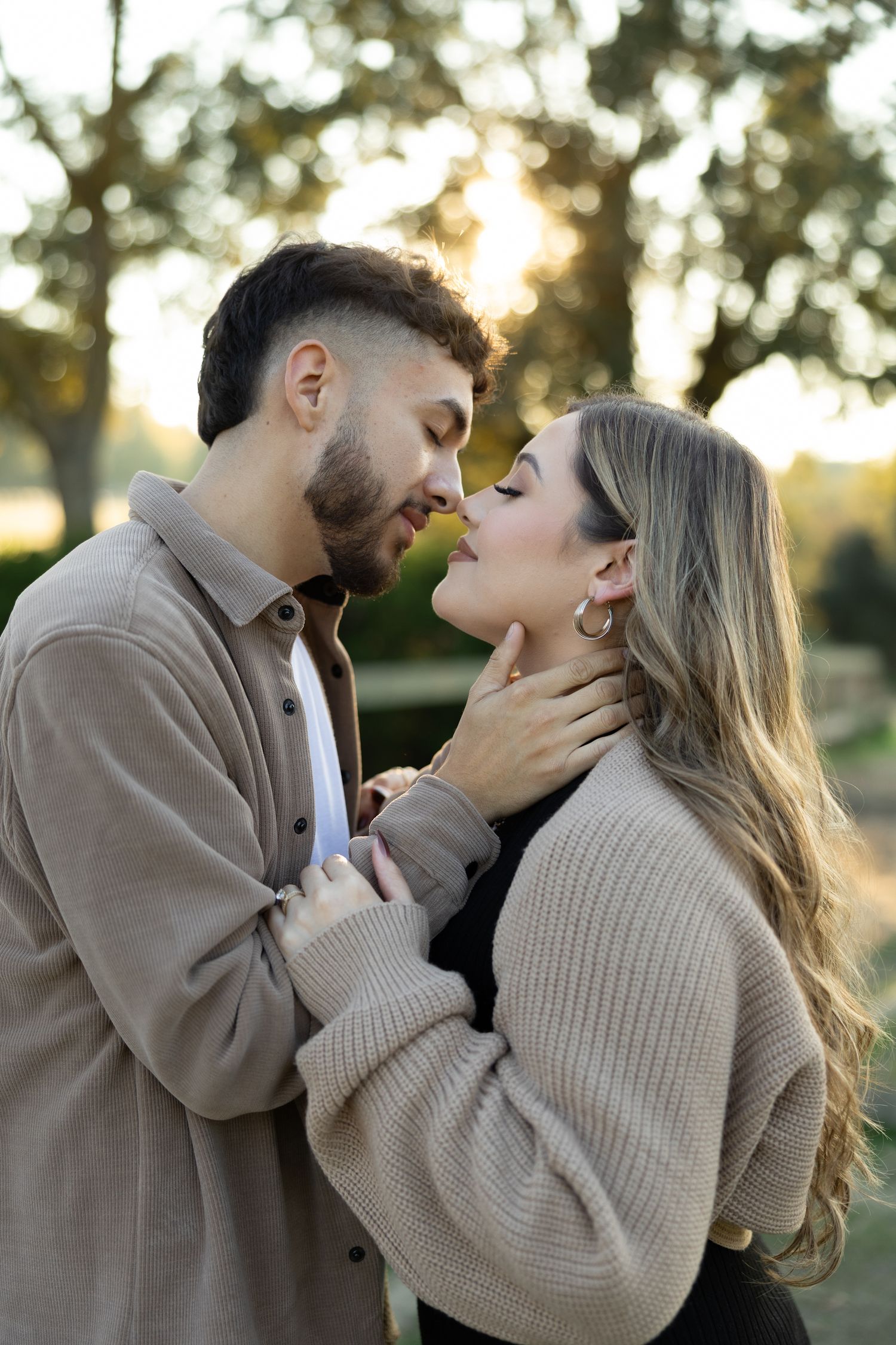 Intimate moment between couple in casual sweaters during golden hour.