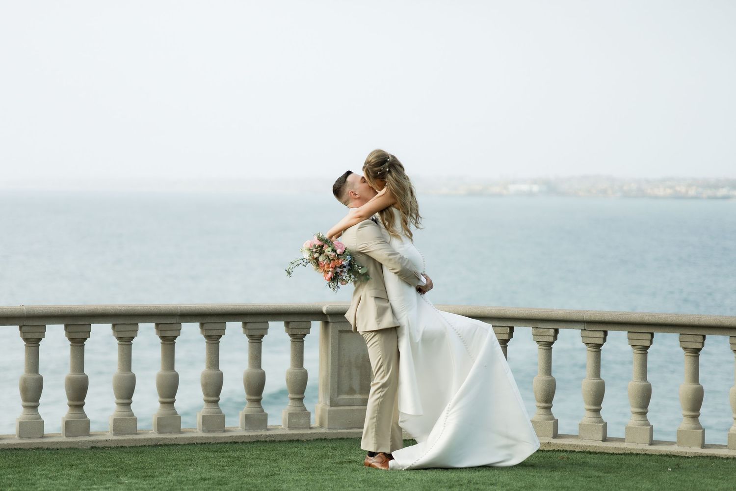 Wedding couple shares romantic moments on an elegant balcony overlooking a scenic view.
