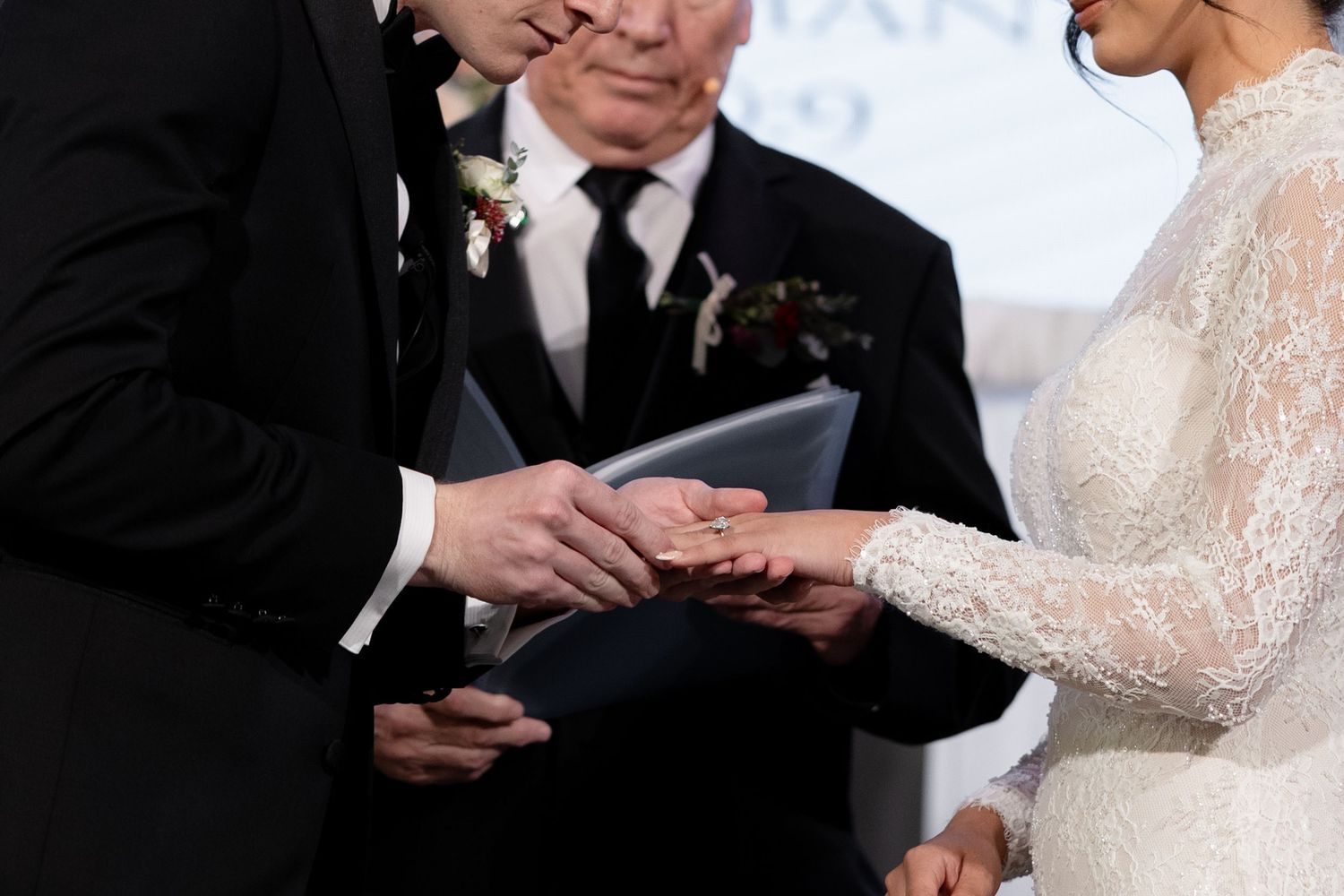 Groom placing wedding ring on brides finger during wedding ceremony exchange of vows.