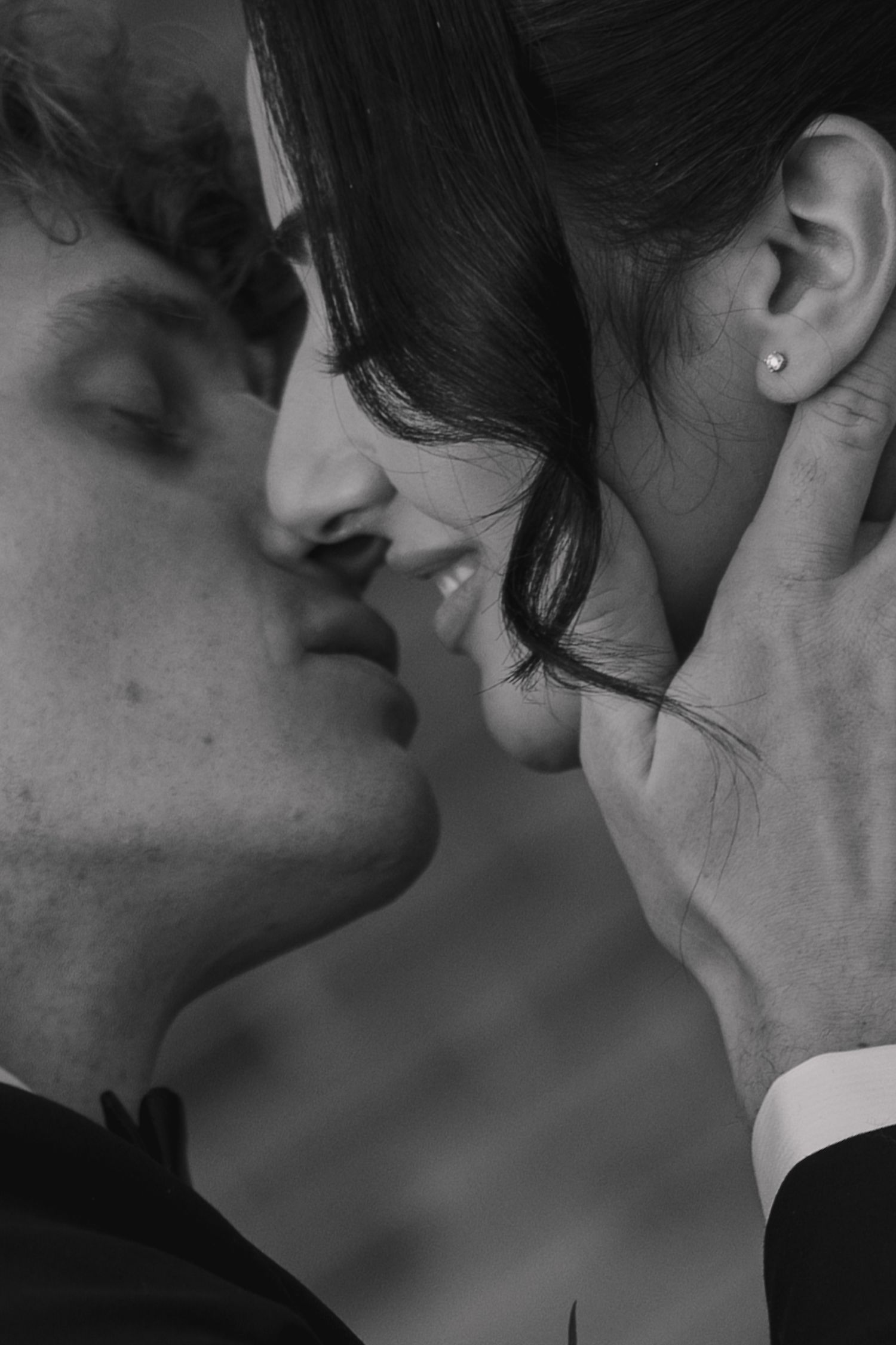Intimate black and white close-up of bride and groom sharing a romantic kiss.