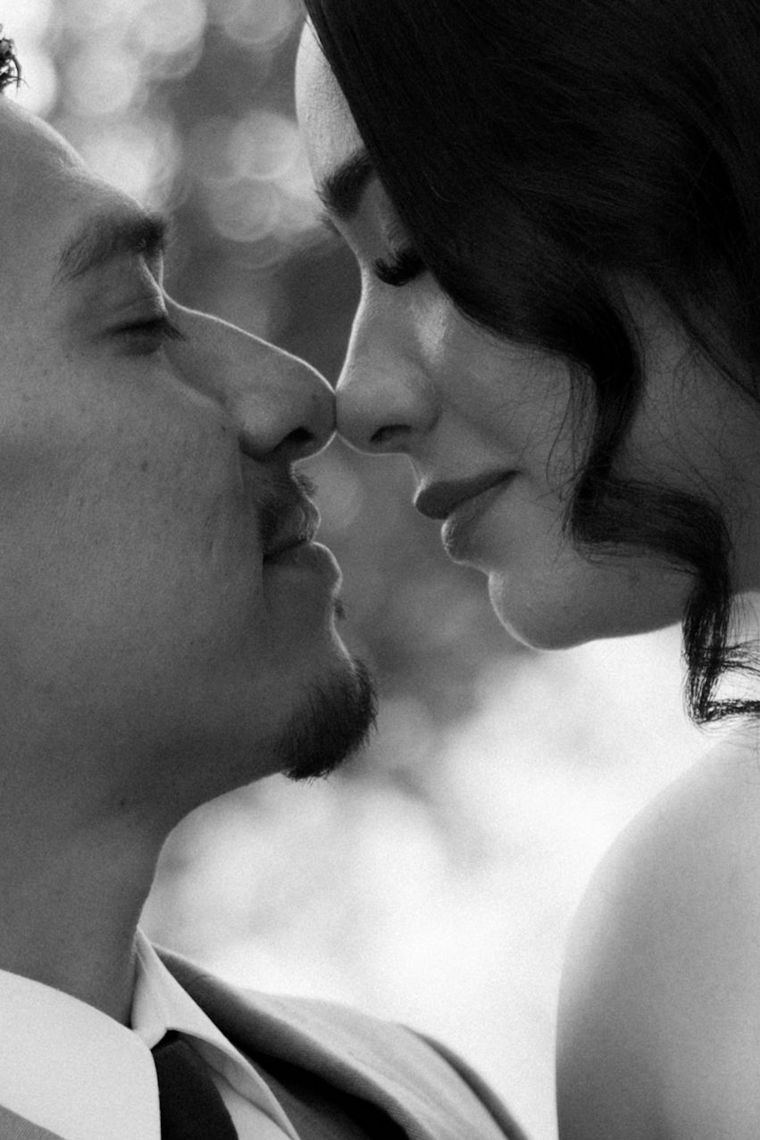 Black and white close-up of a romantic couple about to kiss, capturing an intimate wedding moment.