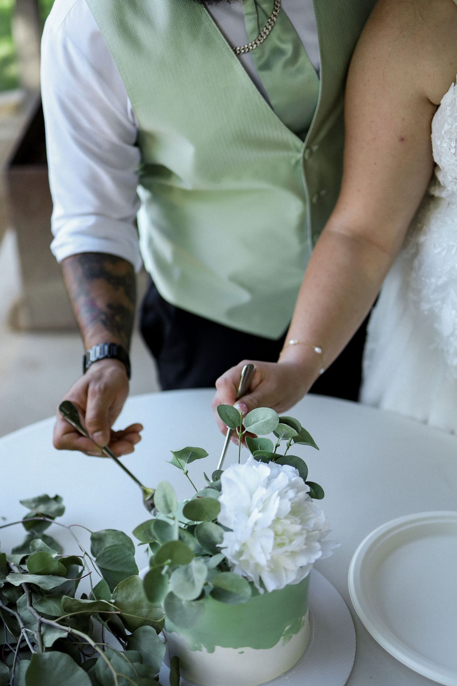 Hands arranging white flowers in a mint green vase during wedding reception setup.