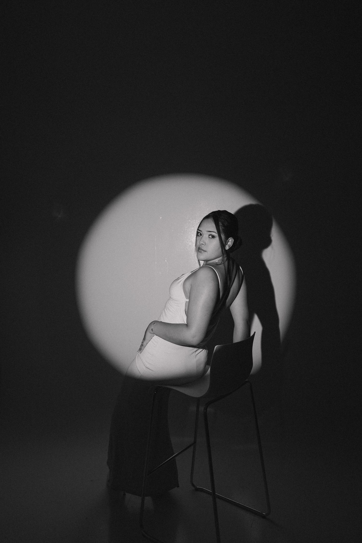 Dramatic black and white portrait with spotlight creating strong shadows and silhouettes.