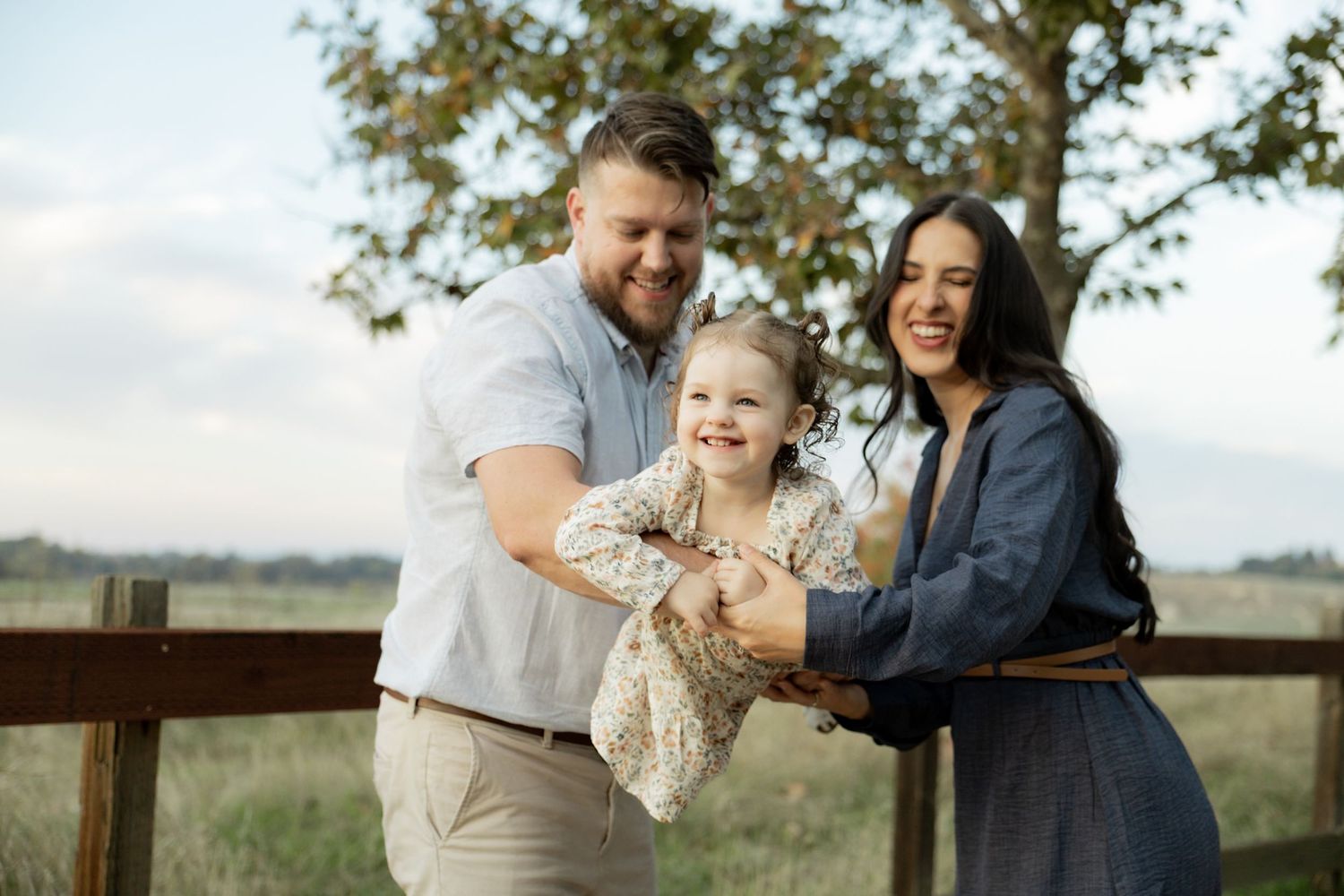 Family enjoying a candid moment together outdoors in a field during sunset.