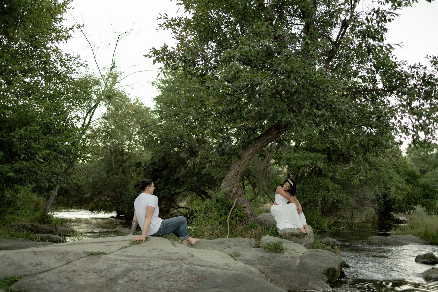 A series of outdoor photos showing a couple walking and sitting together along a scenic riverbank on a sunny day.