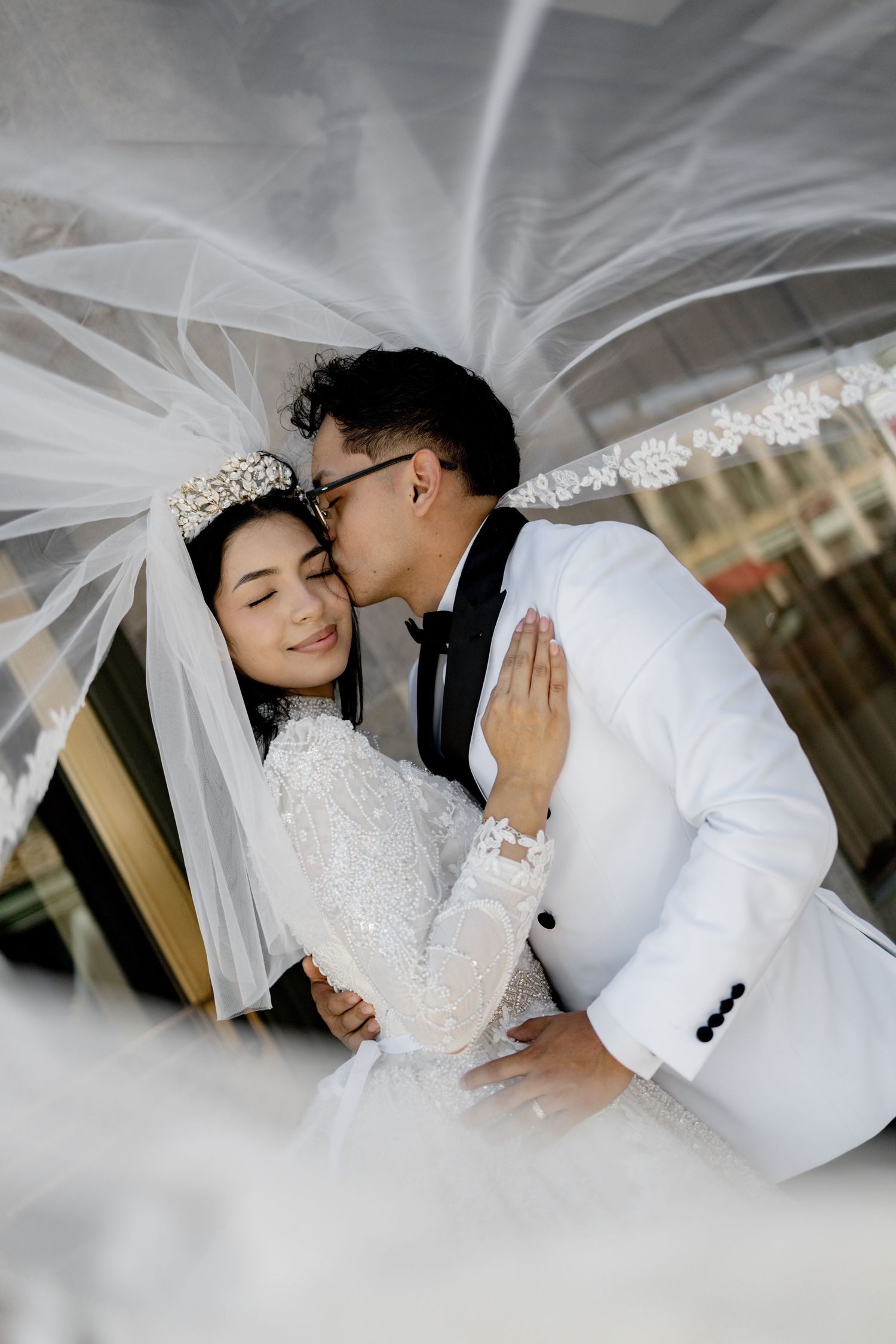 Romantic wedding portrait sequence under a flowing white veil showing tender moments between newlyweds.