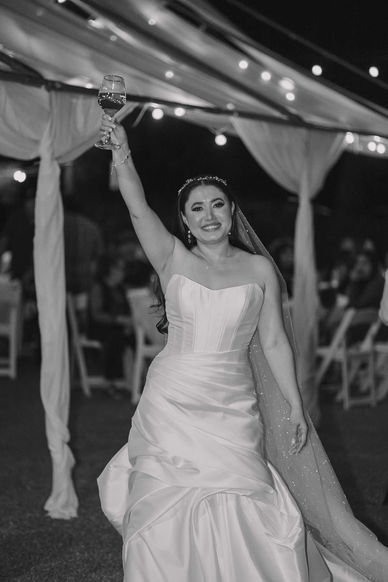 Joyful reception moments under string lights with bride dancing in elegant white gown.