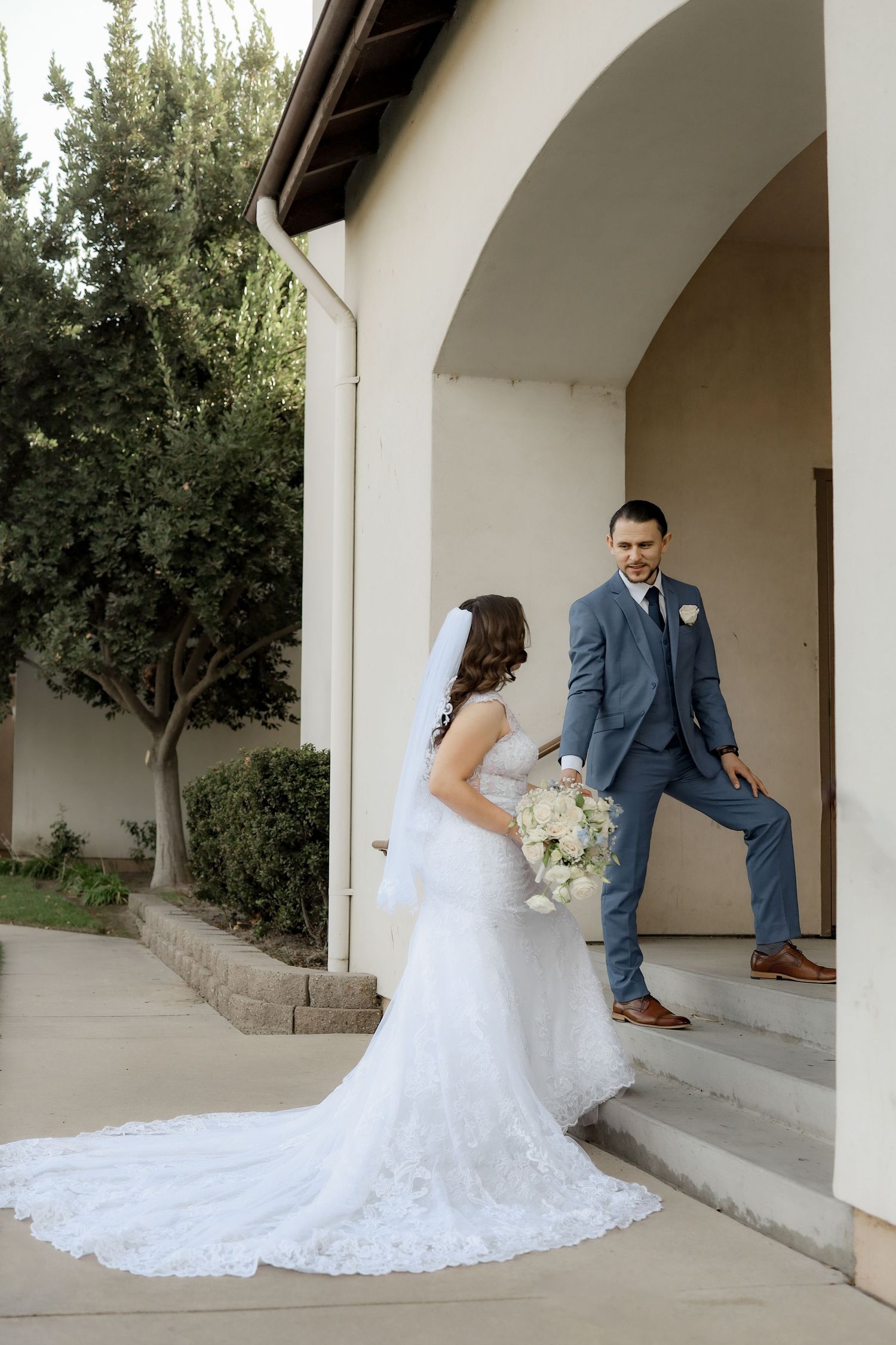 Wedding couple poses together under white arched walkway for romantic portraits.