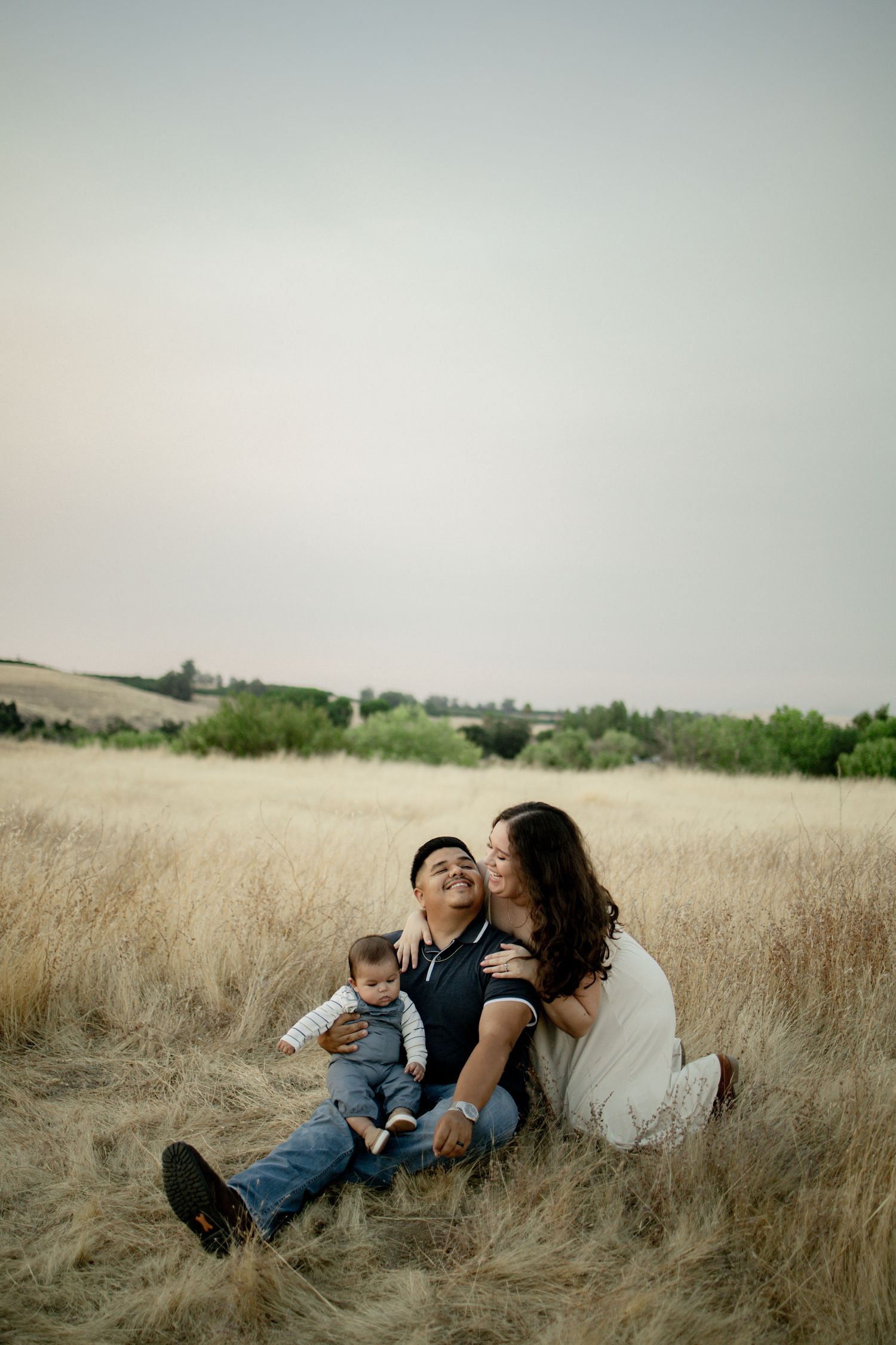 A family relaxing together in a golden wheat field during sunset.