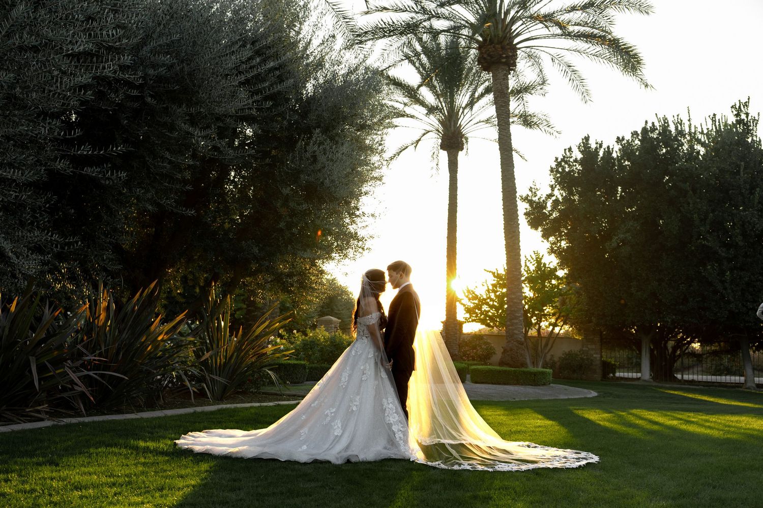 Silhouettes against sunset with palm trees and flowing wedding dresses creating a romantic scene.