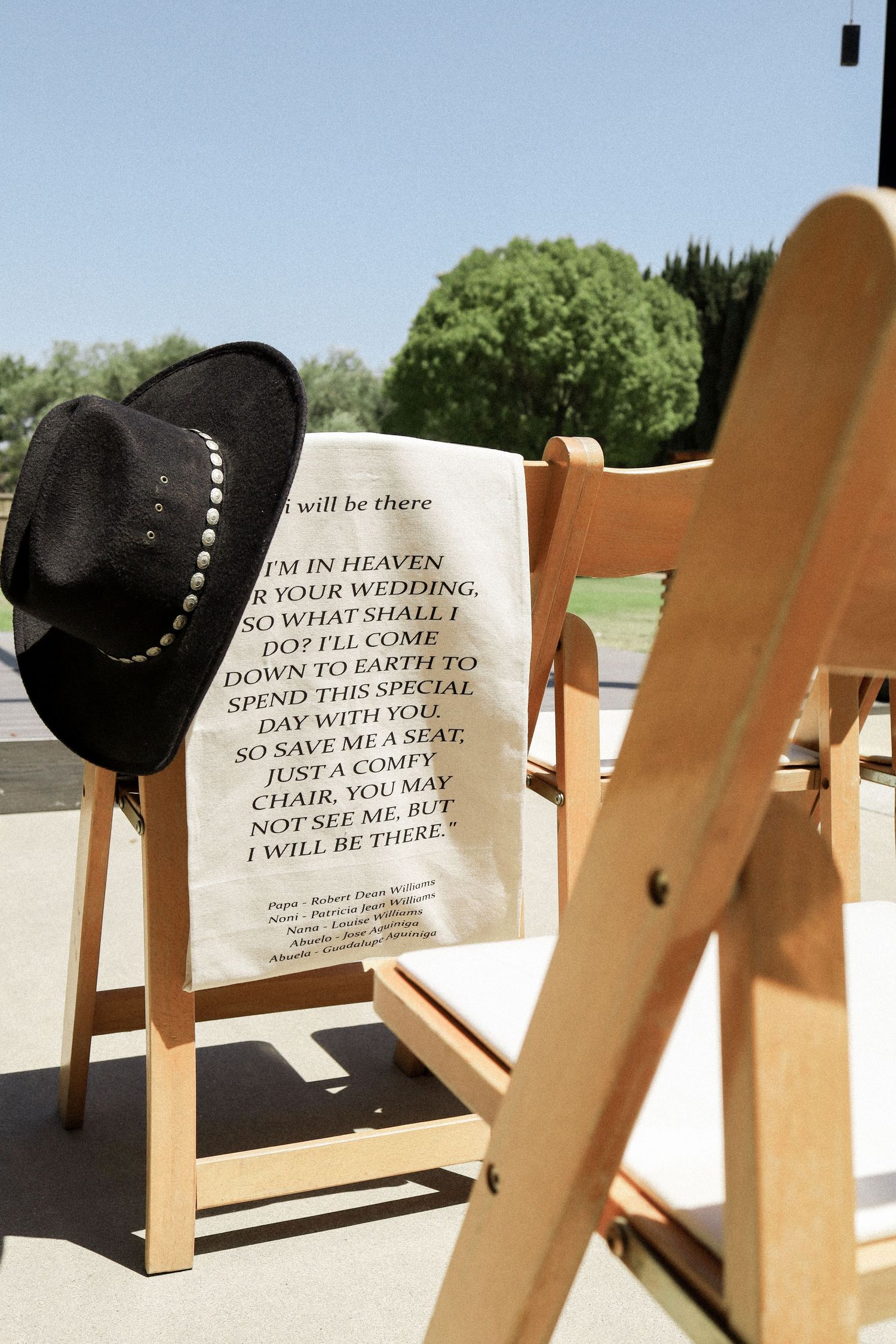 Empty wooden chairs at outdoor ceremony with memorial sign for loved ones in heaven.