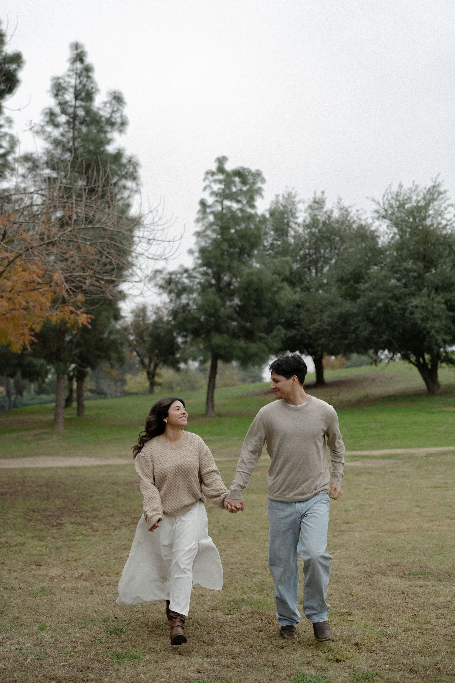 Couple walking together in a park with trees on an autumn day.