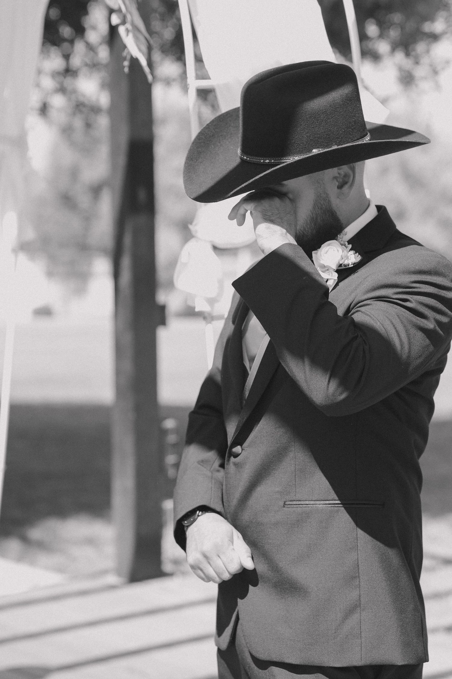 Couple in western attire sharing an intimate black and white moment outdoors.