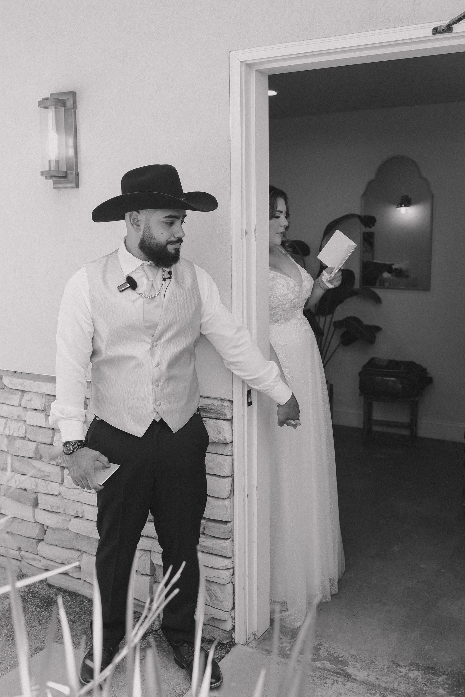 Black and white photo of men in formal attire preparing in a stone-walled room.