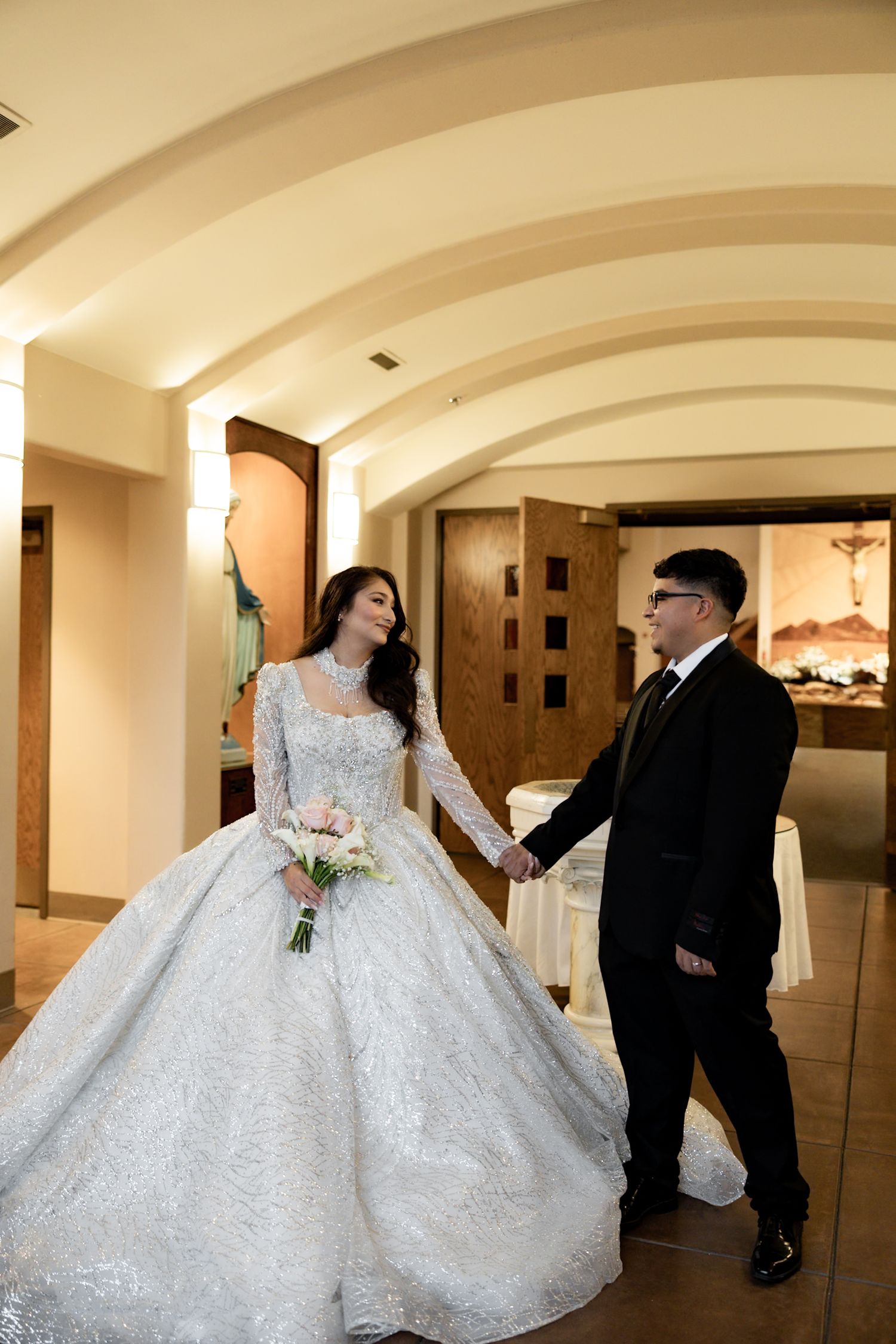 Elegant ballroom with arched ceilings showcasing a flowing white wedding gown.