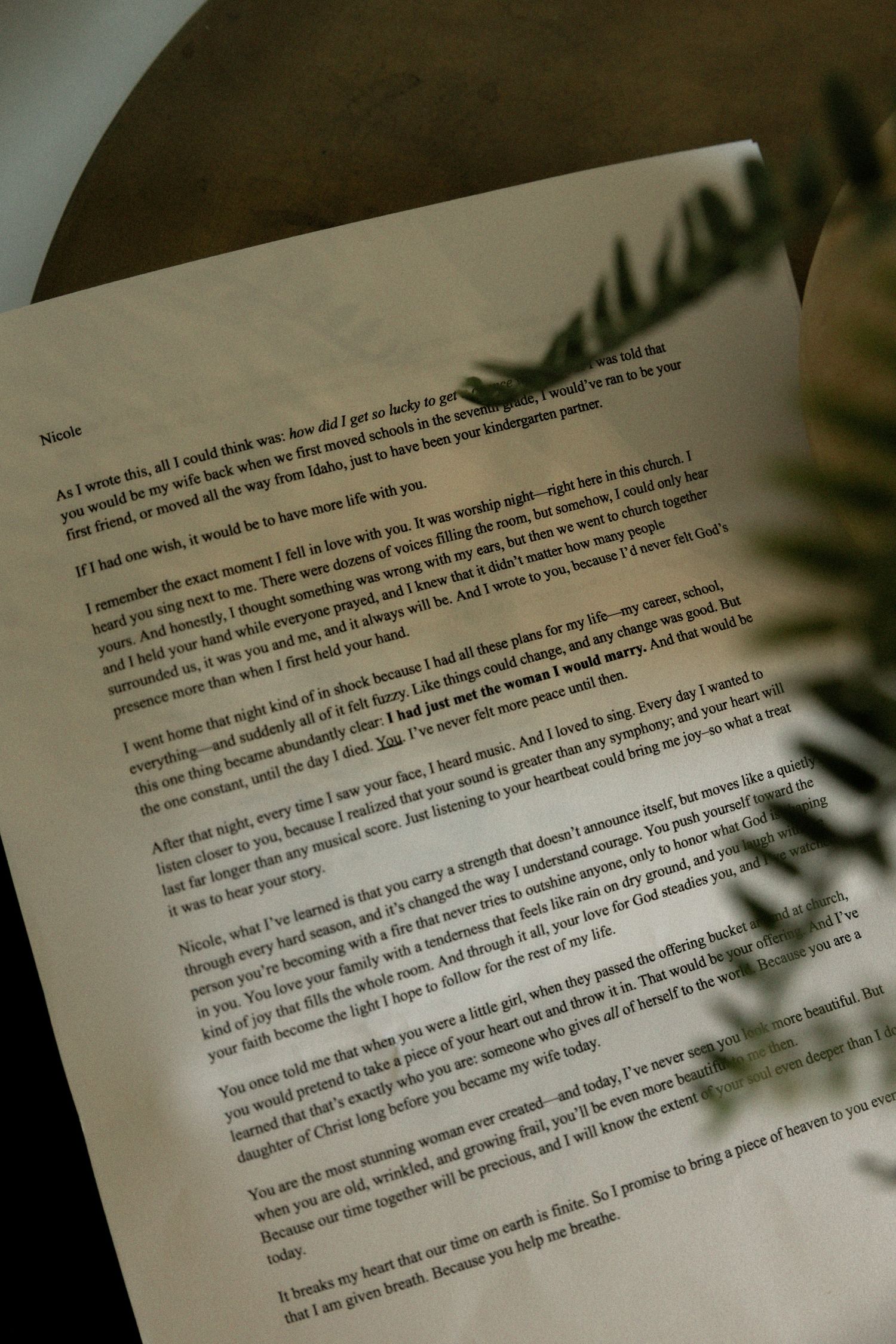 Handwritten wedding letter on aged paper with heartfelt vows, placed near greenery.