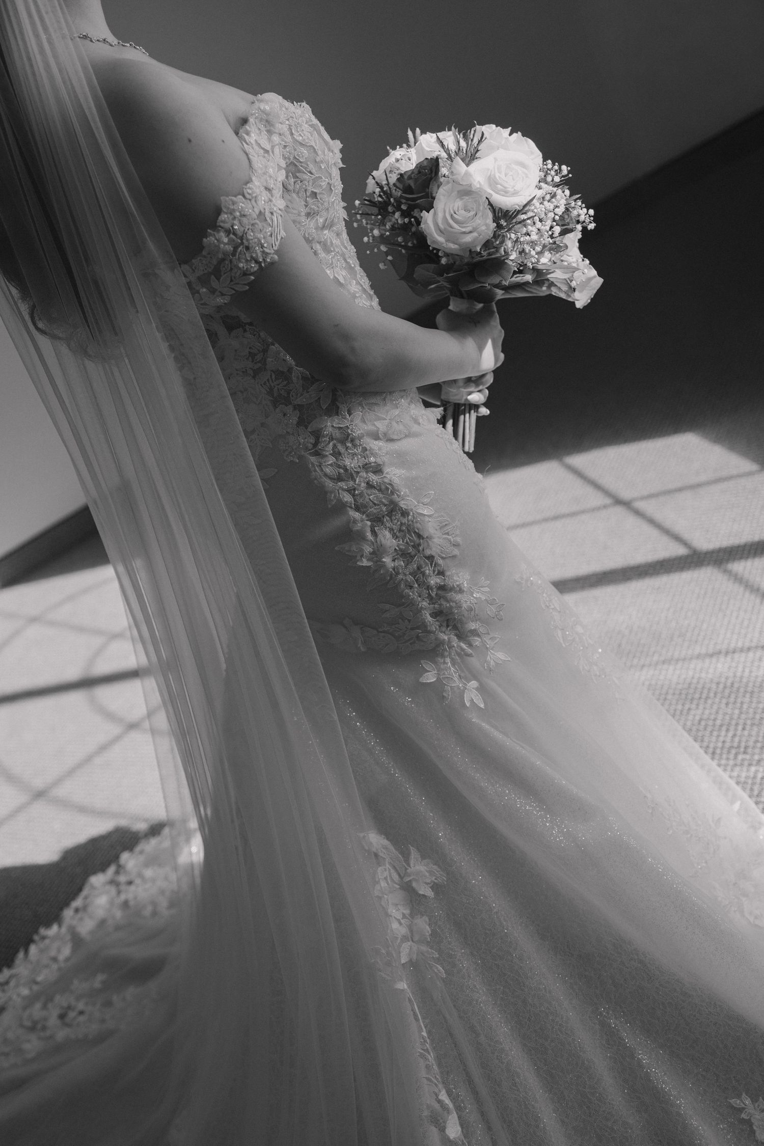 Dramatic black and white photos showcasing intricate lace details of a wedding gown.