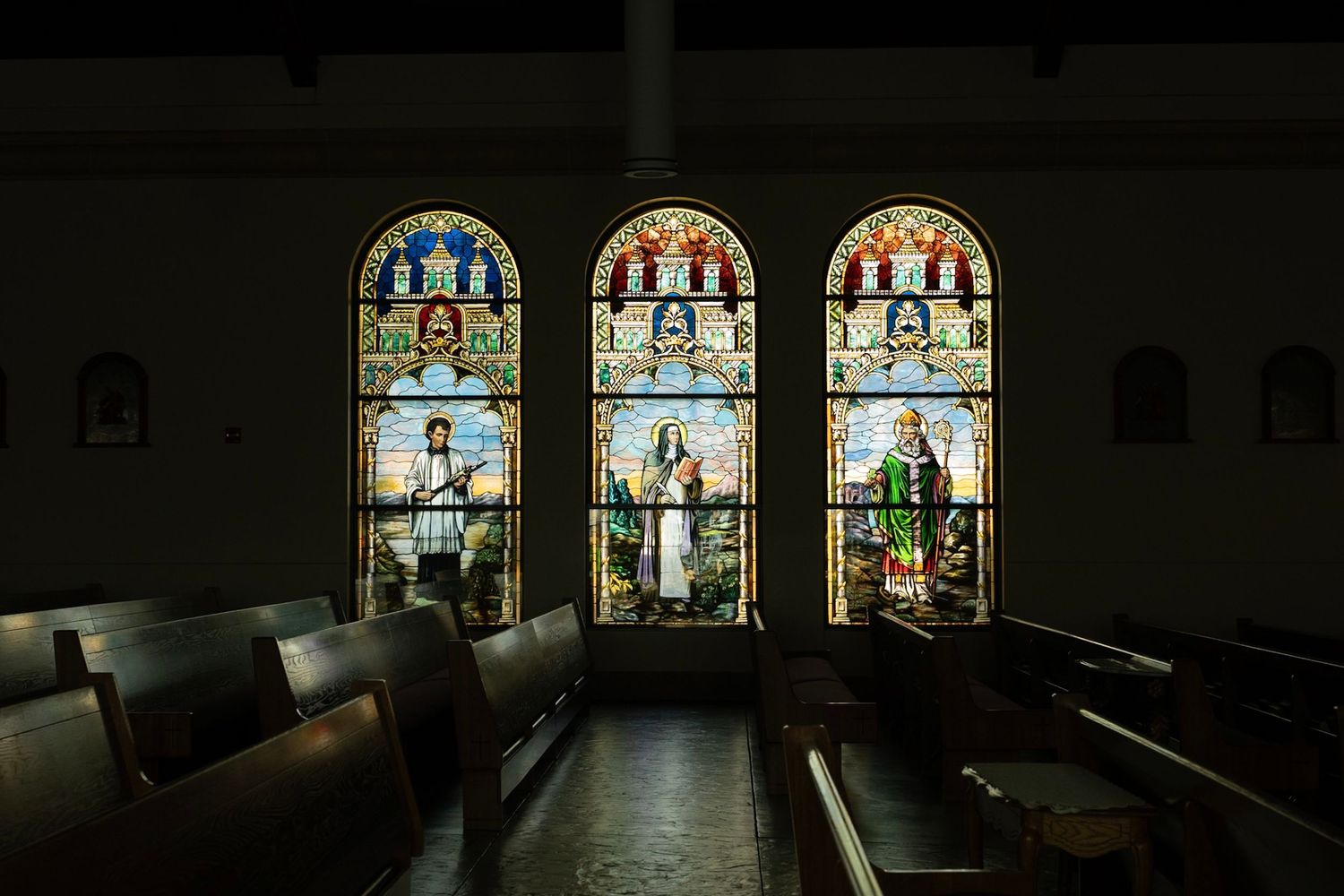 Panoramic view of illuminated stained glass windows in a church interior.