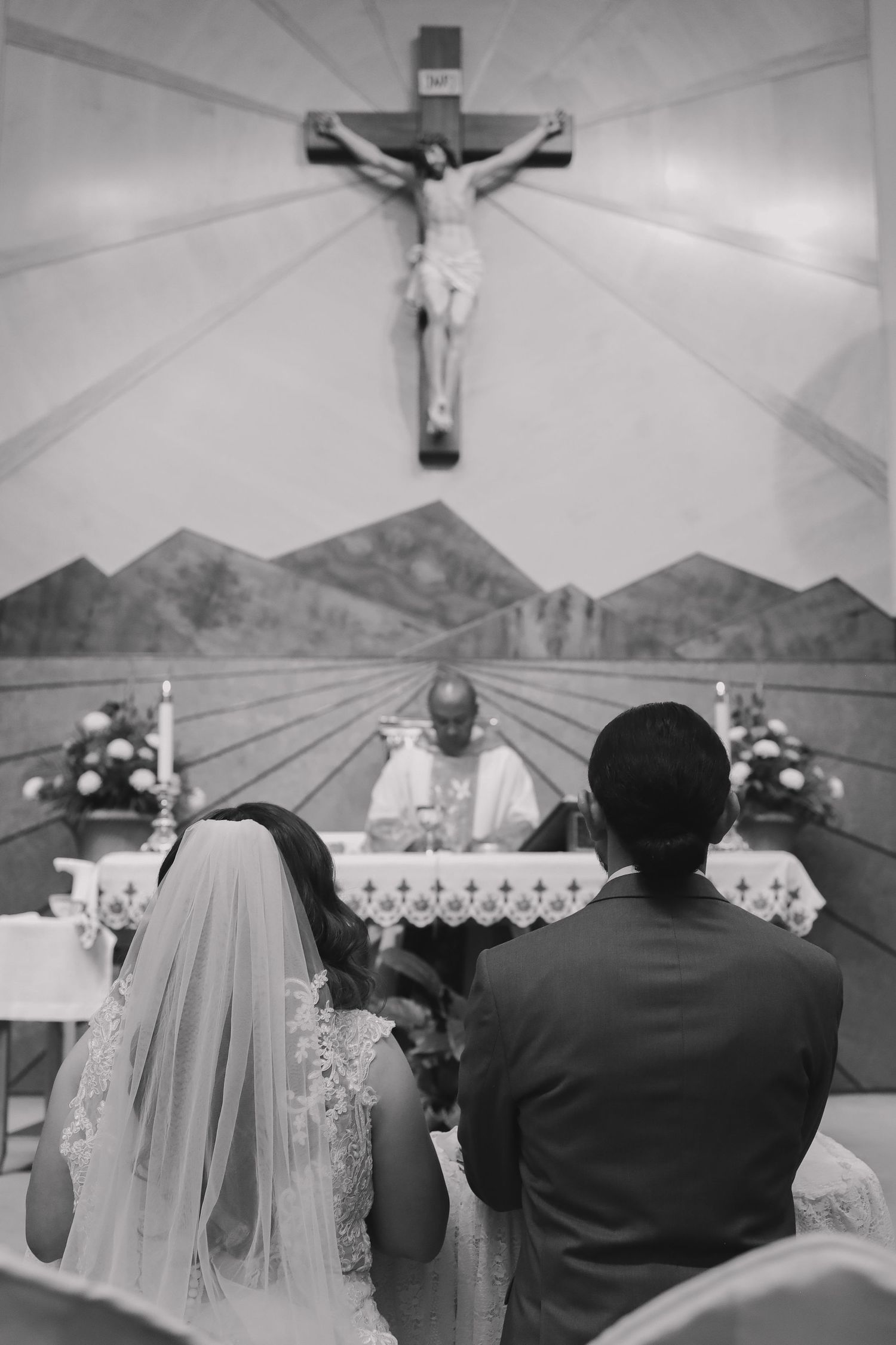 Wedding ceremony setup under white tent with crucifix and mountain backdrop.