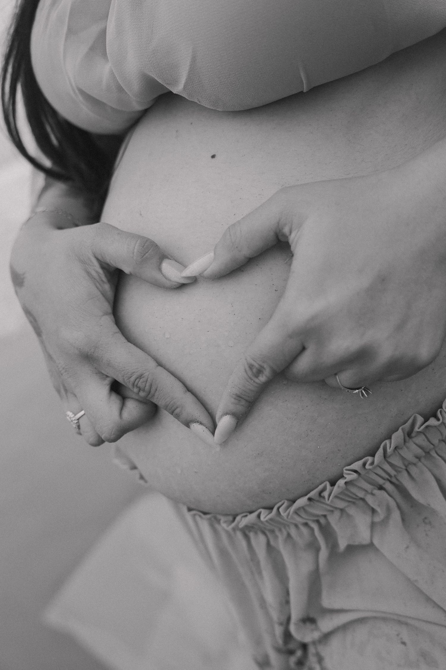 Black and white photo series showing hands gently cradling a pregnant belly in various intimate poses.