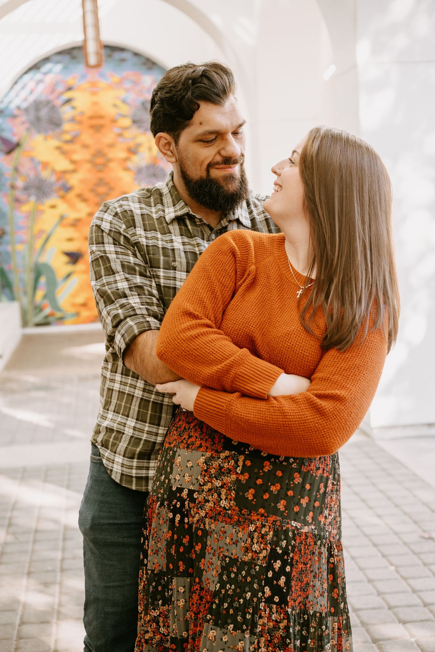 Couple in autumn sweaters sharing intimate moment under white archway.