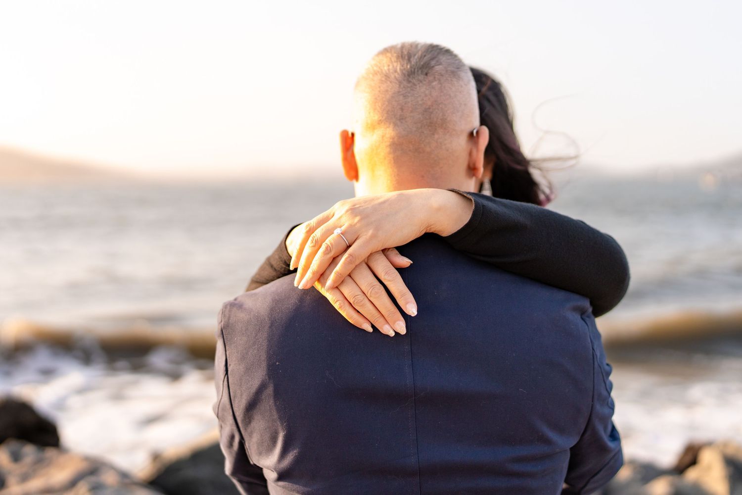 Tender embrace captured in silhouette against ocean backdrop at dusk.