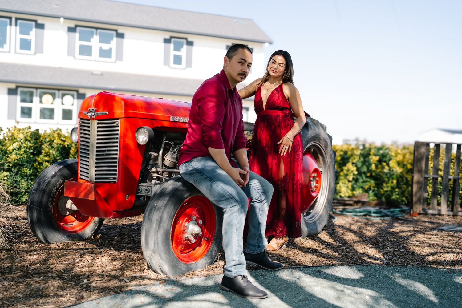Couple in red outfits posing with a vintage red tractor at Serendipity Cellars Winery