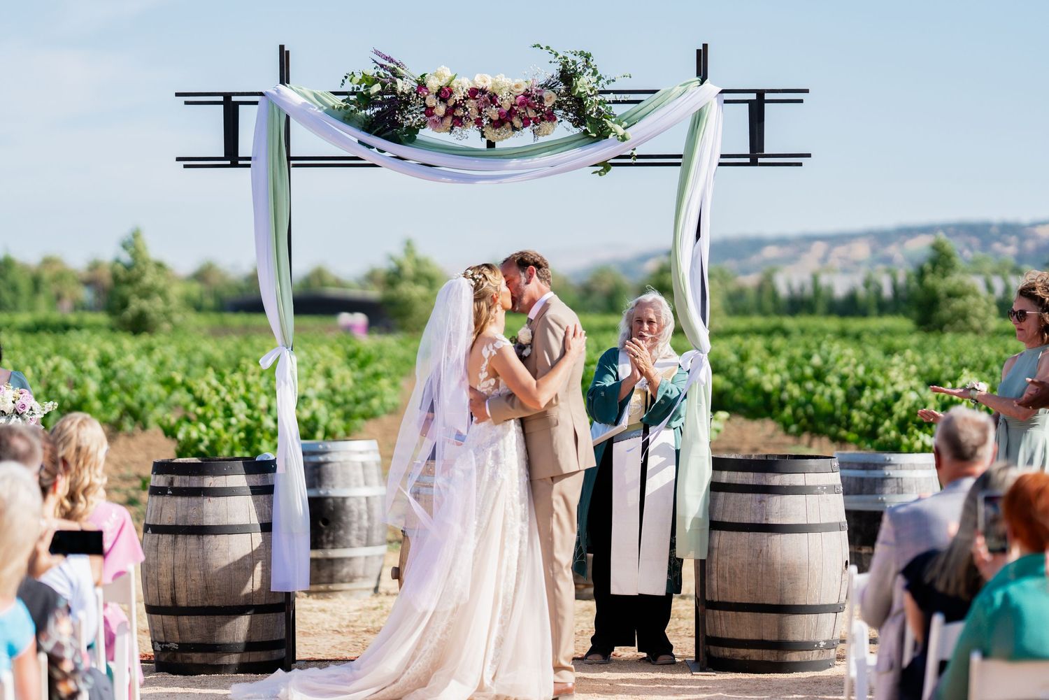 Vineyard wedding ceremony site with decorative arch and wine barrel details.