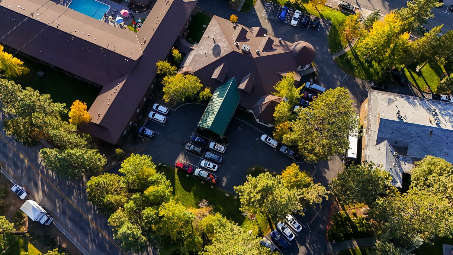 Aerial view of residential houses with green trees and landscaping from above Forest Suits Resorts