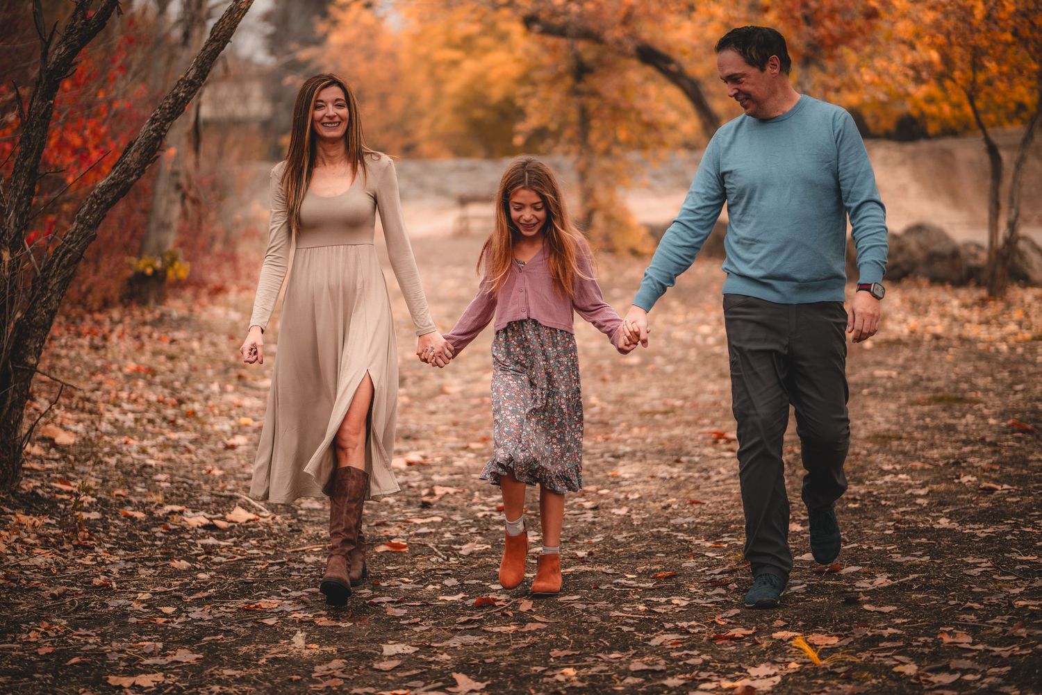 Family enjoying a stroll through a park with vibrant orange fall foliage.