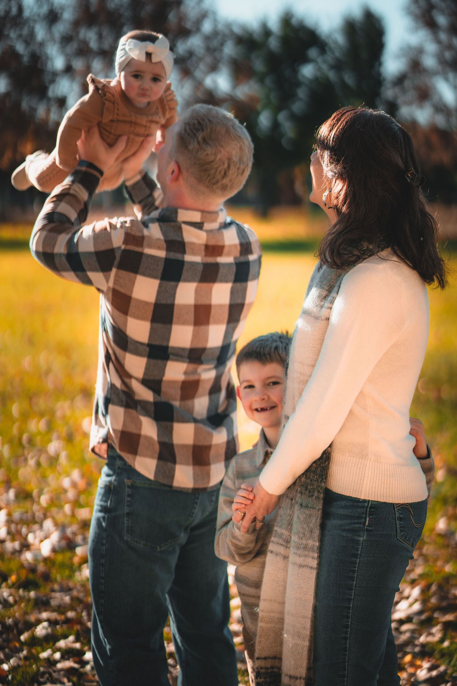 Family holding hands while walking through a field during autumn season.