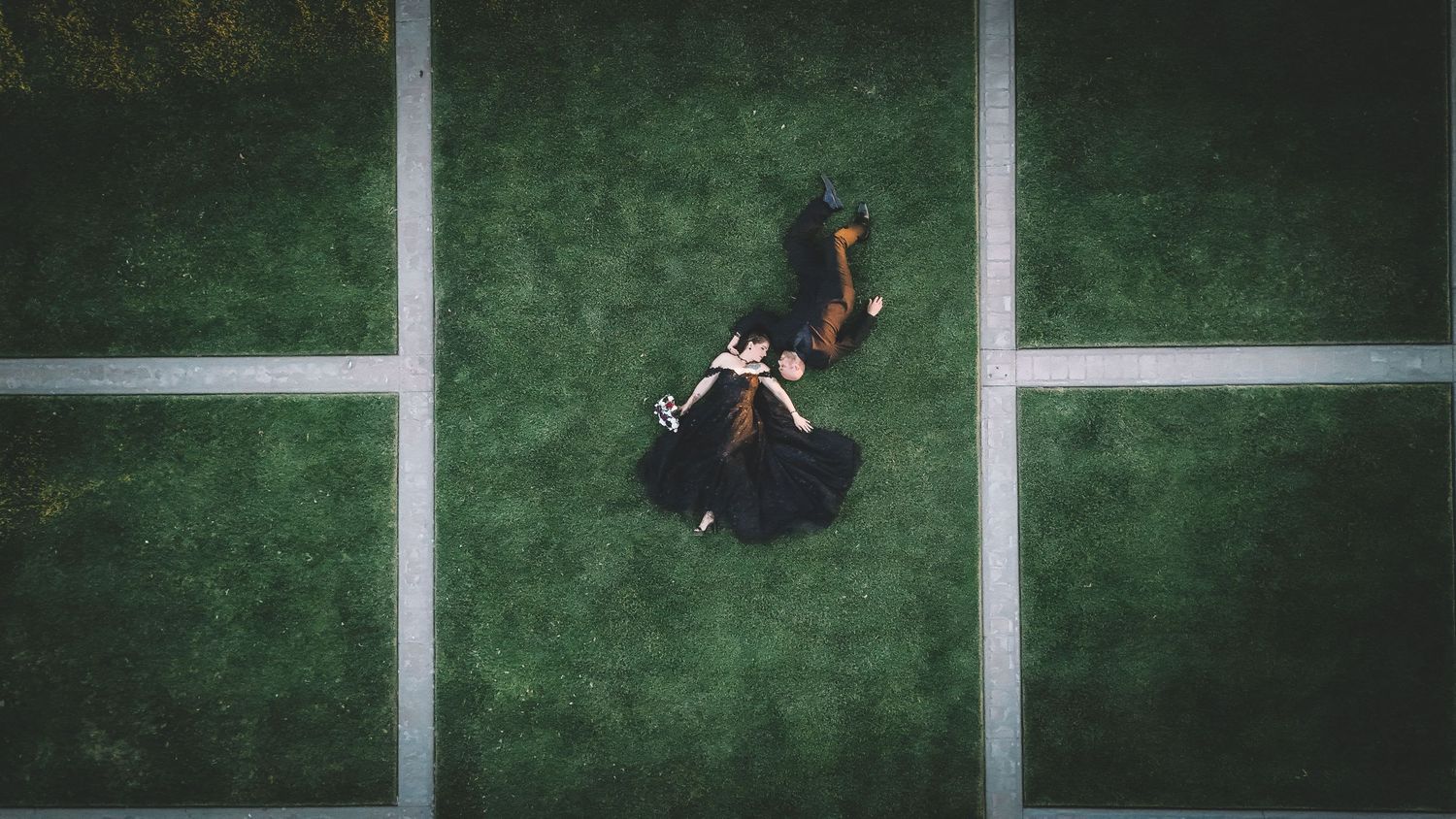 Aerial view of couple dancing on green geometric patterned surface.