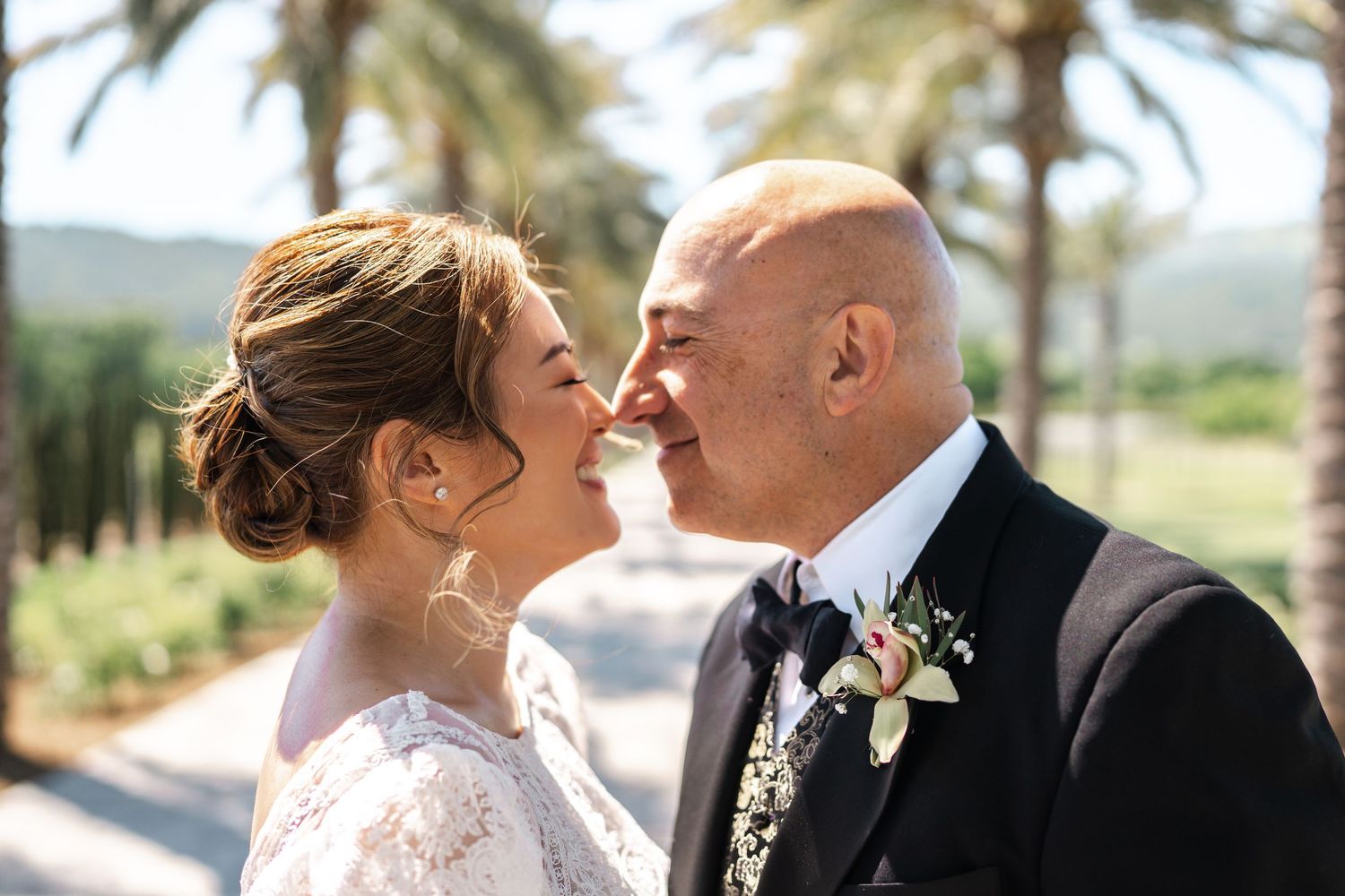 Wedding couple sharing intimate moment in palm tree garden setting.