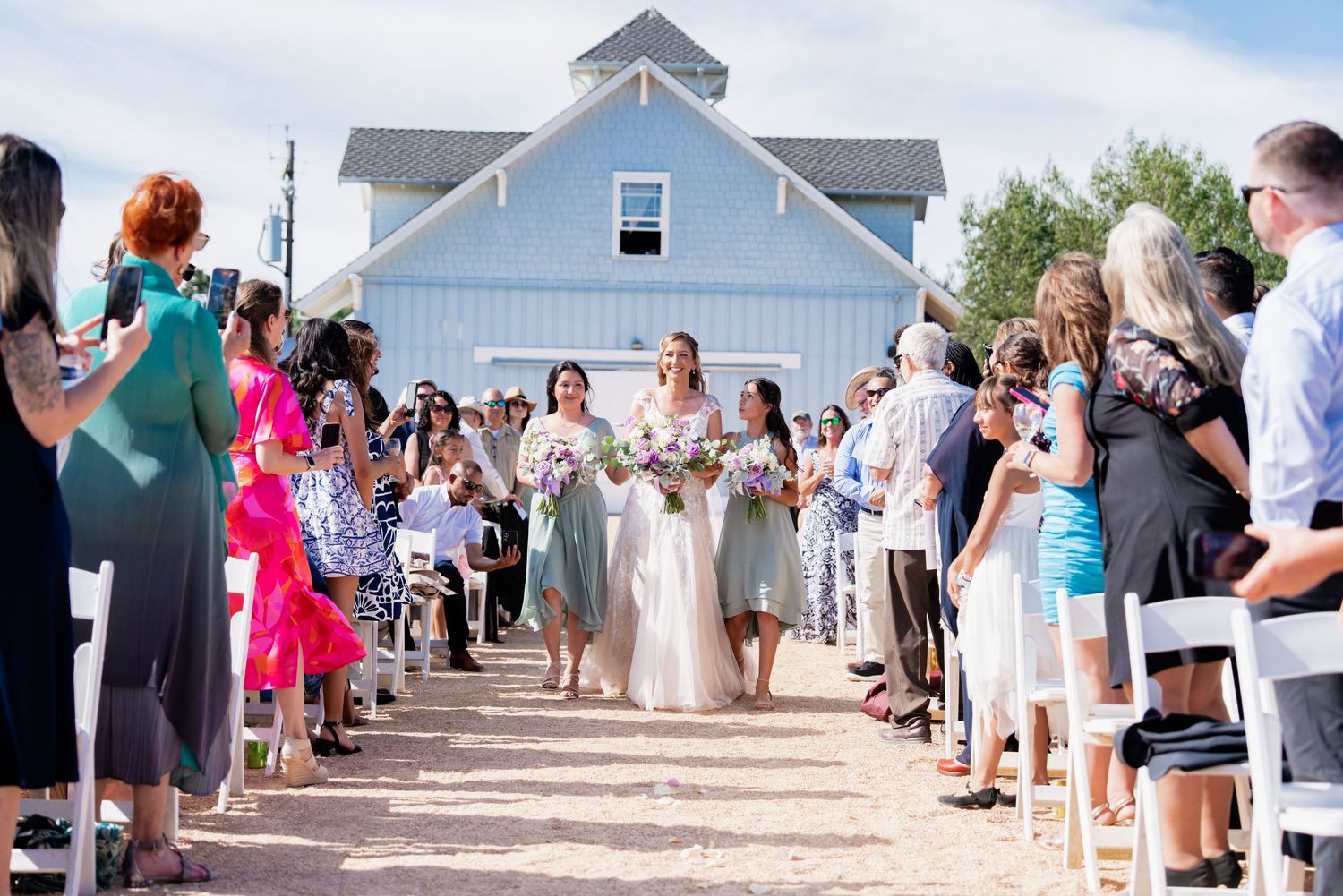 Wedding ceremony guests gathering outdoors at a vineyard venue.
