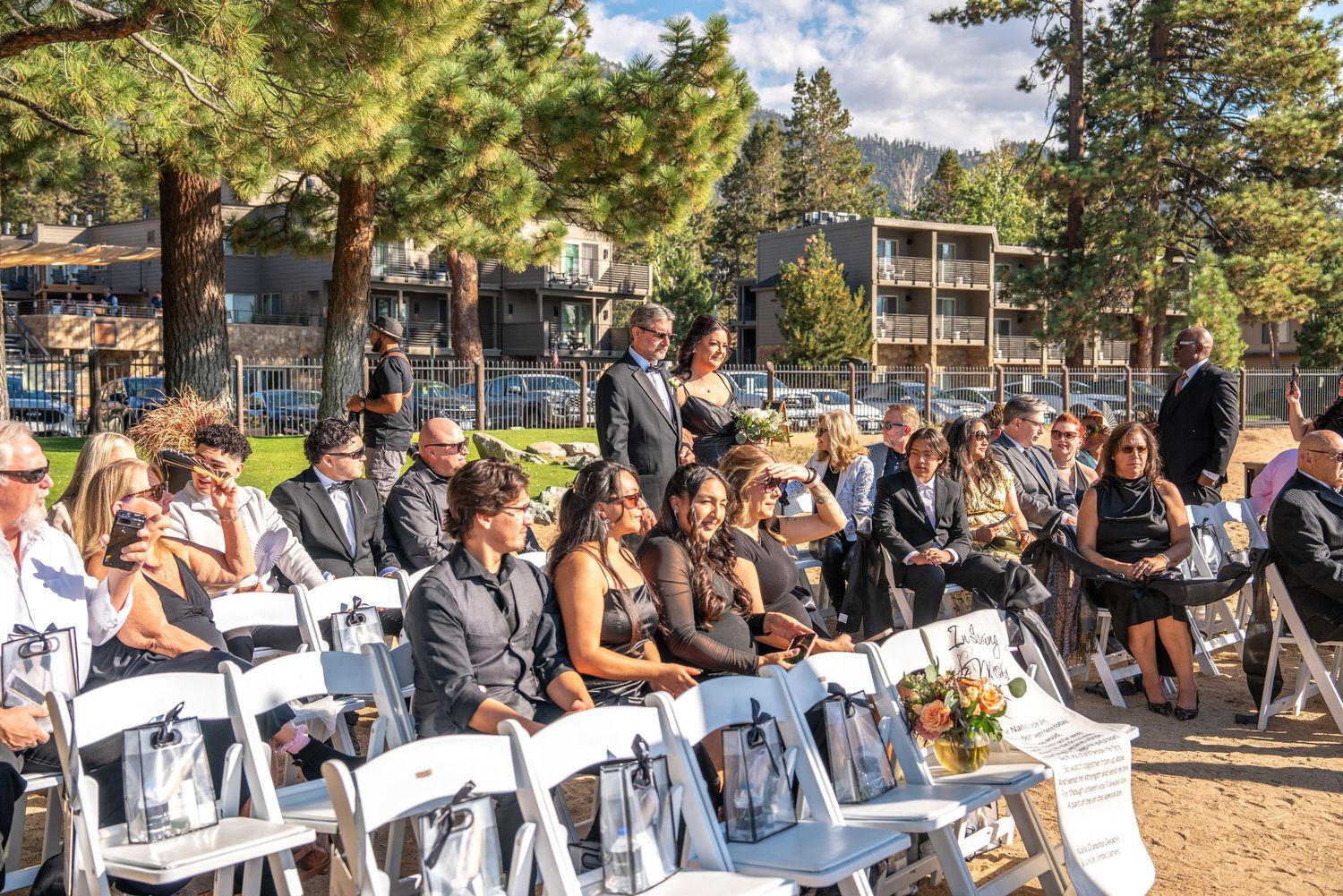 Wedding guests seated in white chairs among tall pine trees during an outdoor ceremony at Forest Suits Resorts Tahoe