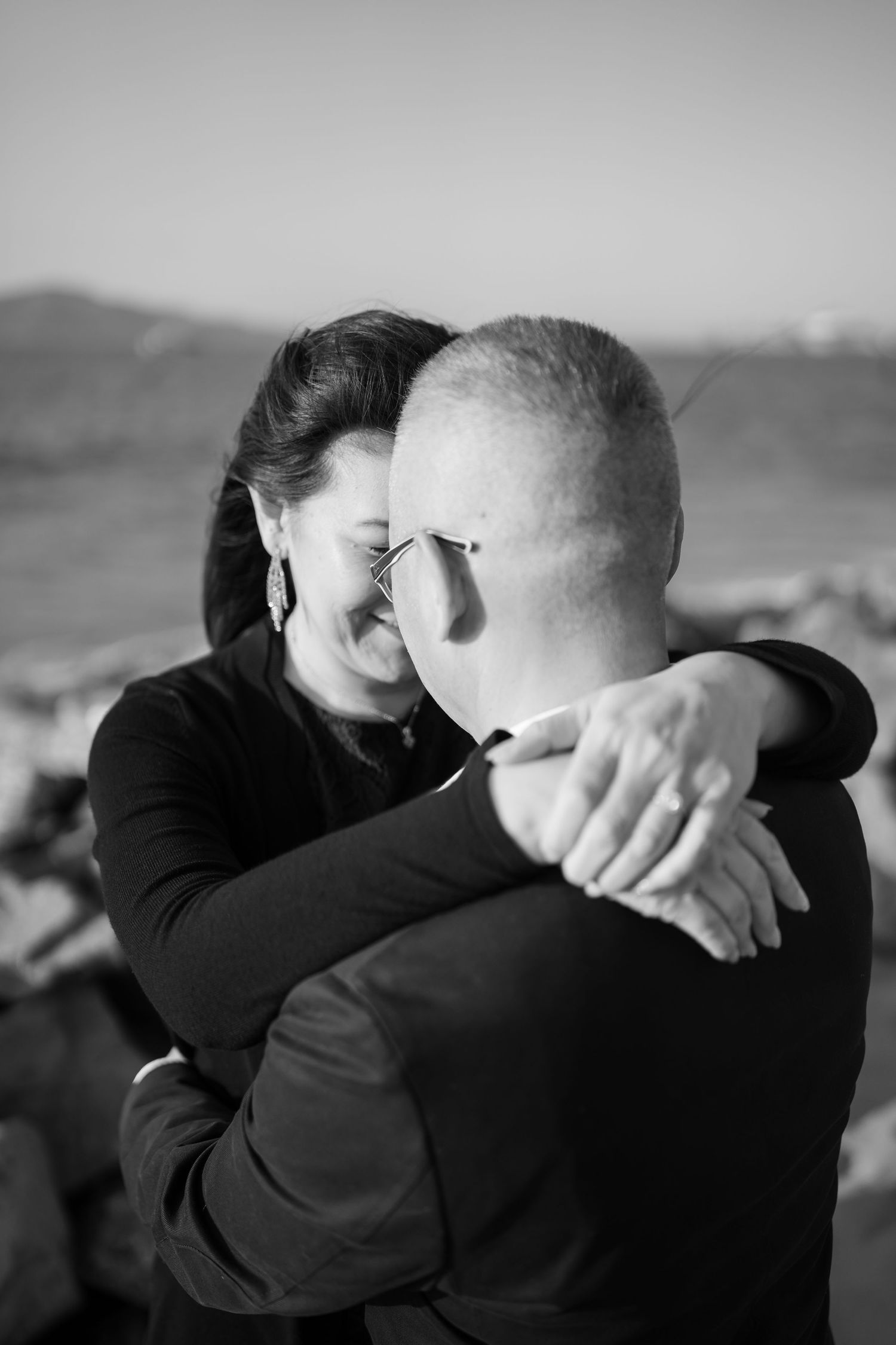 Black and white photo of an emotional embrace at an outdoor gathering.
