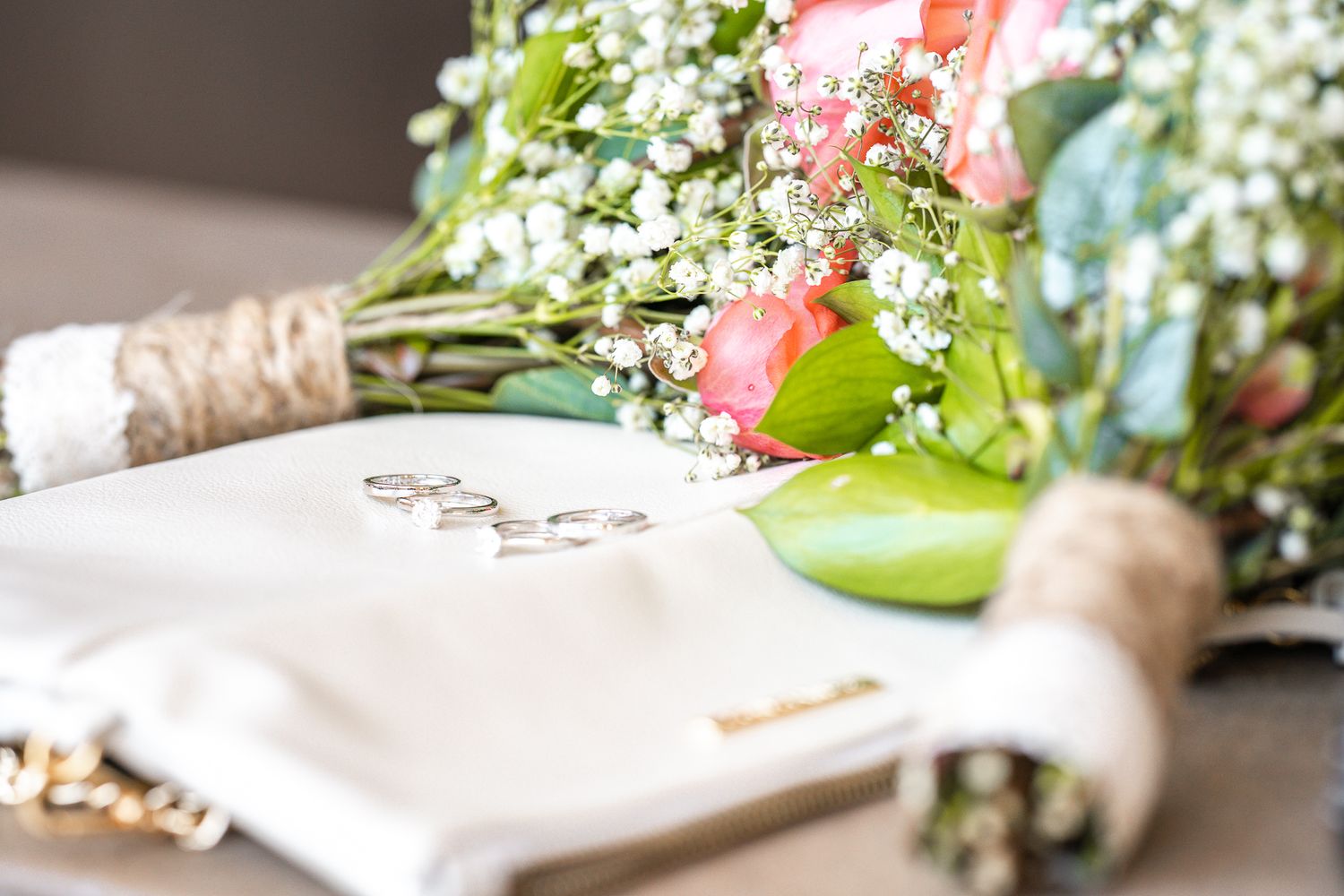 Wedding bouquet with pink roses and white flowers arranged on light surface.