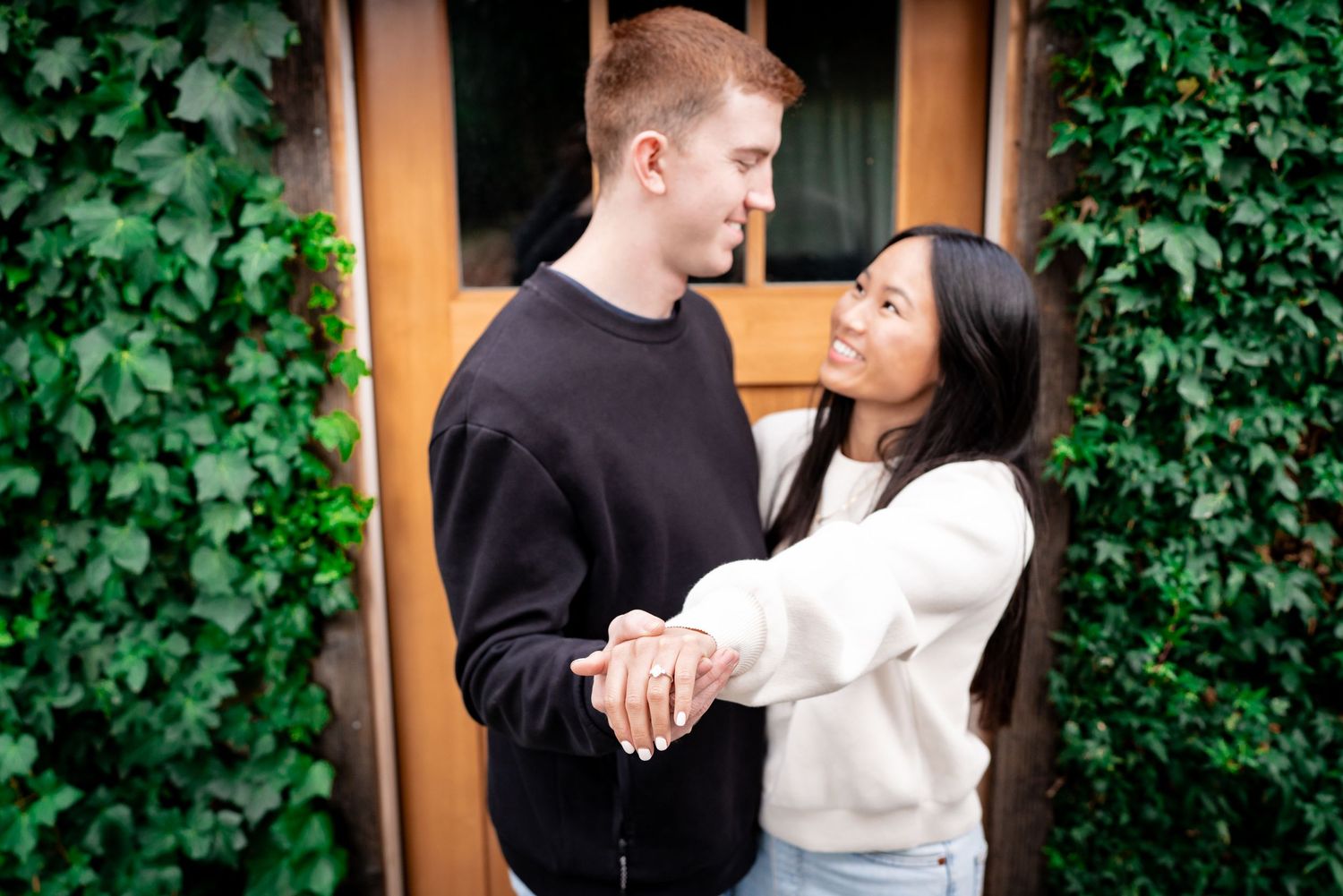 Couple sharing an intimate moment against a wall covered in lush green ivy.