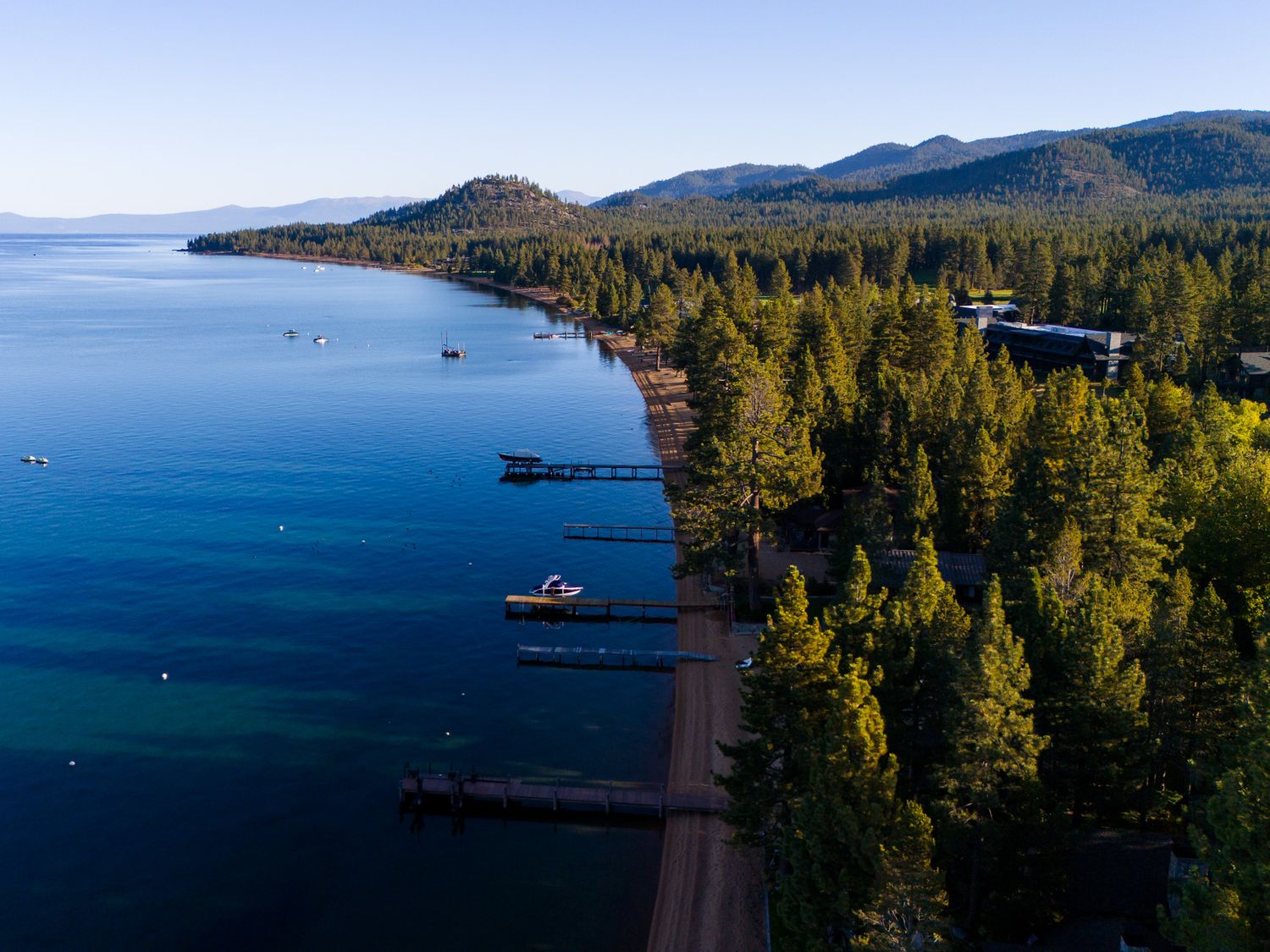 Scenic mountain lake surrounded by evergreen forests and distant peaks in Tahoe