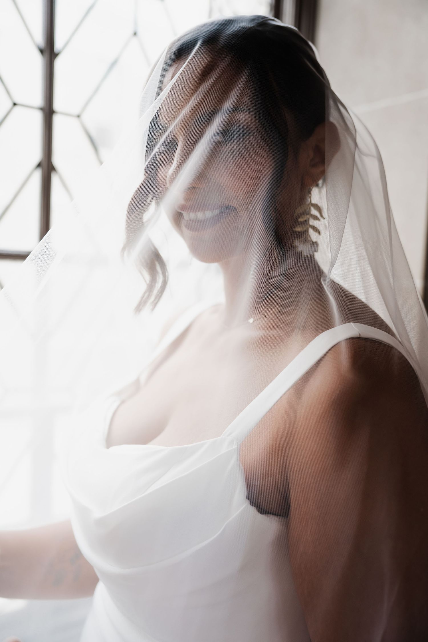 Ethereal bridal portrait with soft light streaming through sheer veil.
