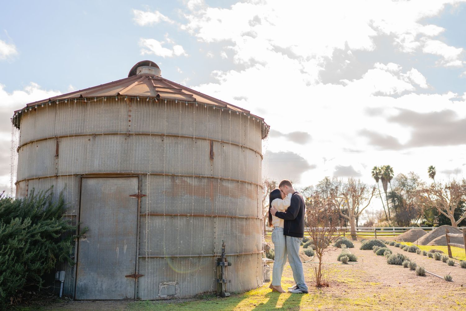 Rustic metal storage tanks stand against a cloudy sky in an industrial setting.