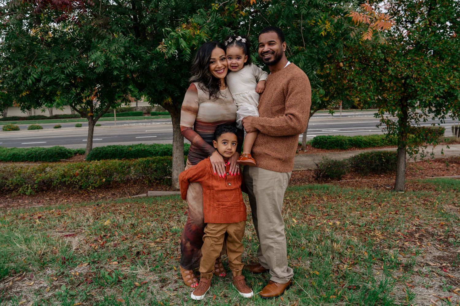 Family strolling together through a park with autumn trees in the background.